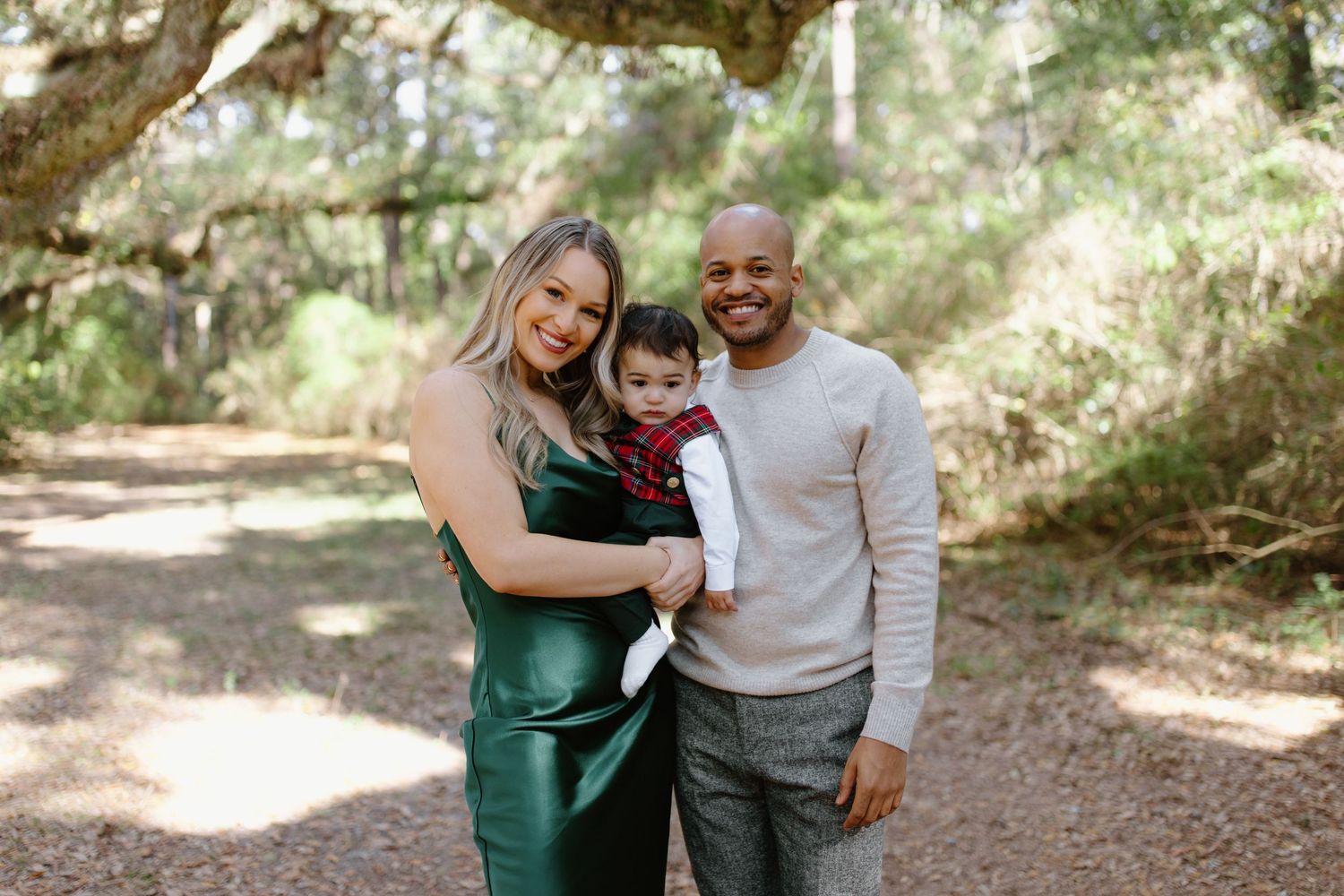 People embrace and laugh together while walking along a wooded trail on a sunny afternoon.