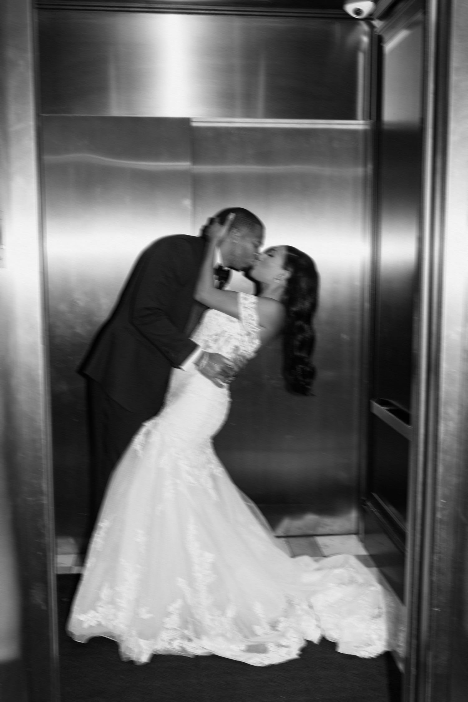 Black and white wedding photograph series showing a romantic sequence of the newlyweds sharing a tender kiss in an elevator.