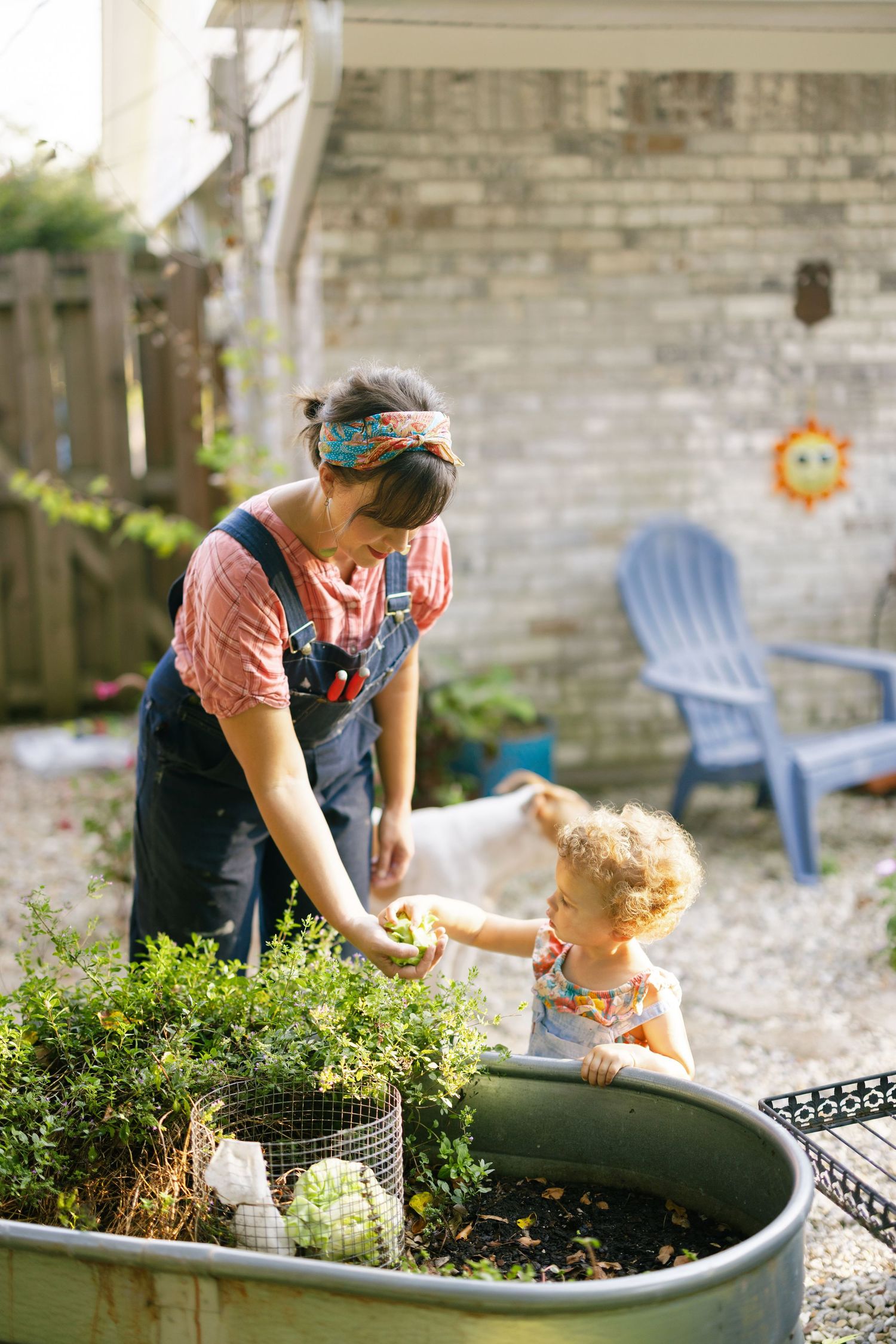 Together planting flowers in a large garden container on a sunny afternoon in the backyard.