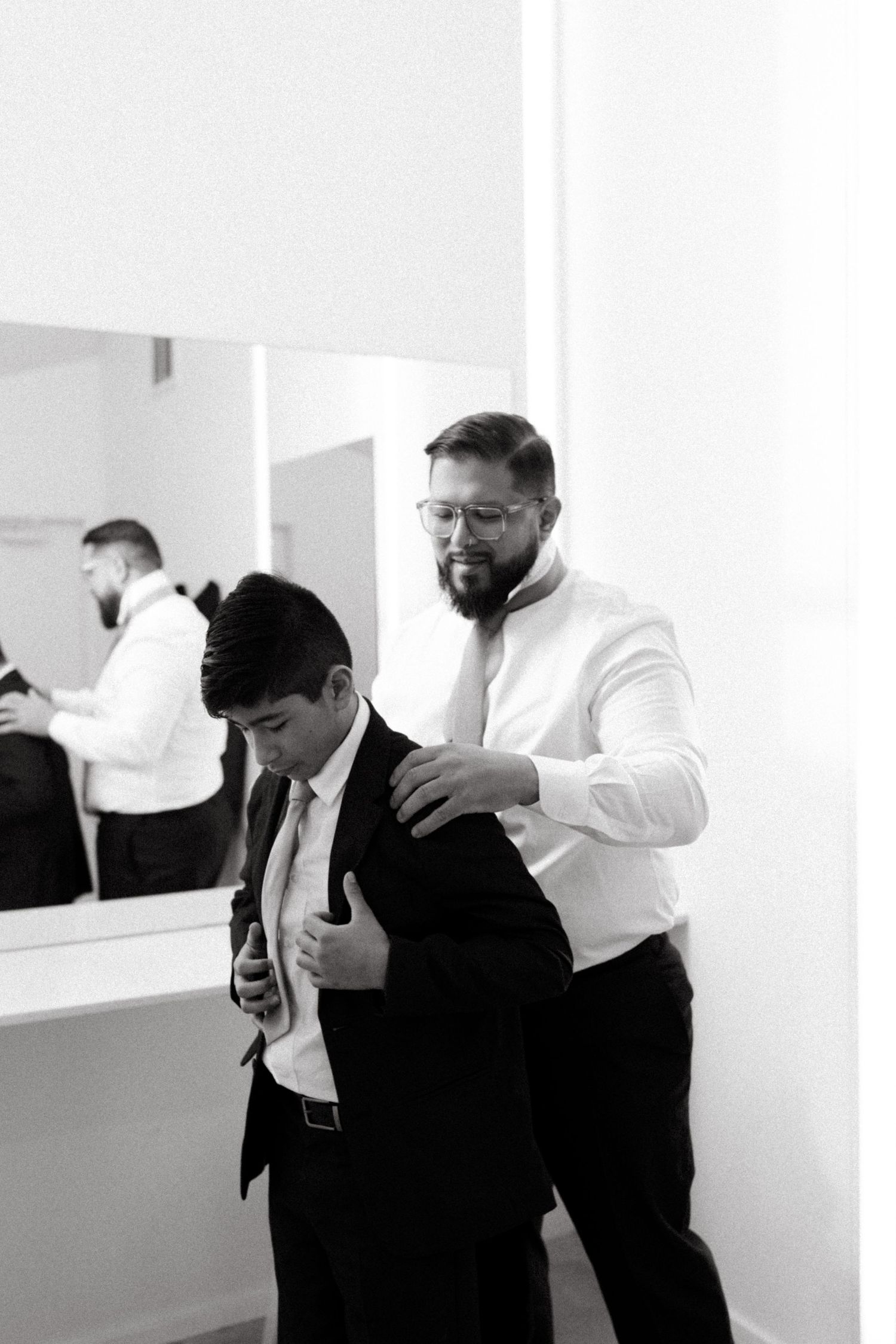Black and white photo series showing businessmen in suits moving through an office hallway during a workday.