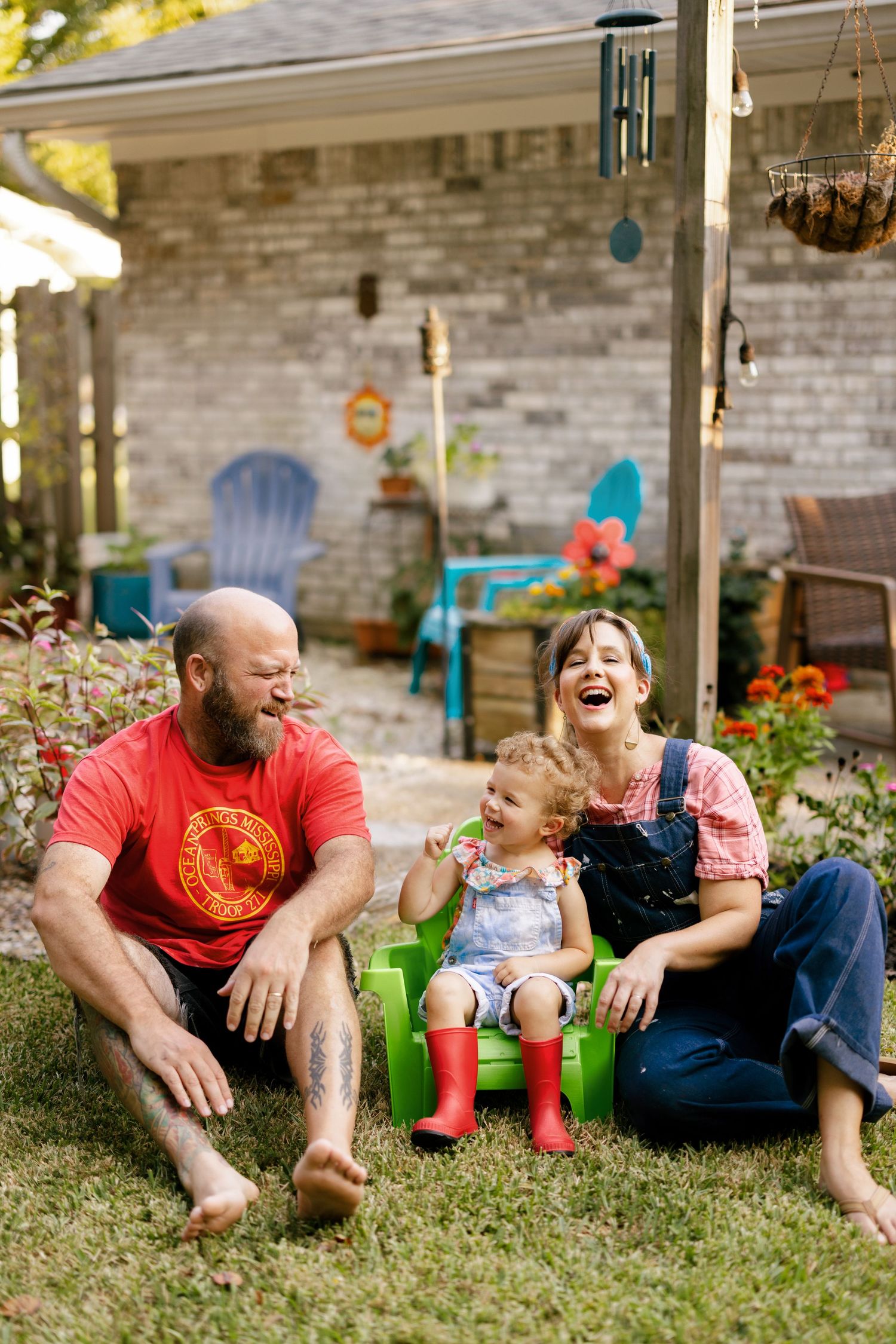 A joyful moment shared on the lawn beside a stone house with casual outdoor seating.