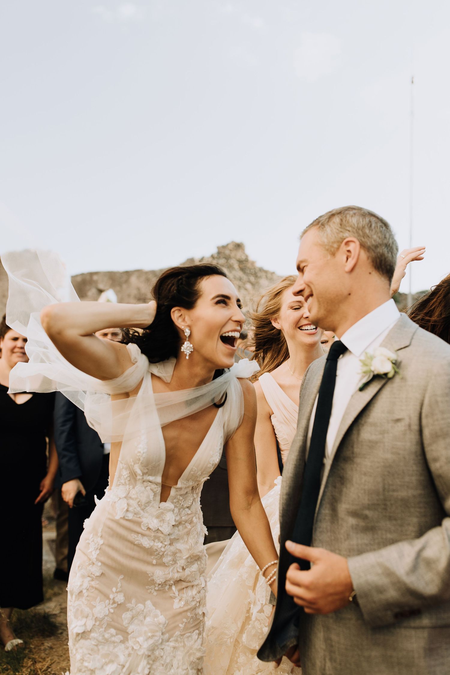 A joyous group dancing together at a wedding celebration, with the bride wearing a delicate lace gown.