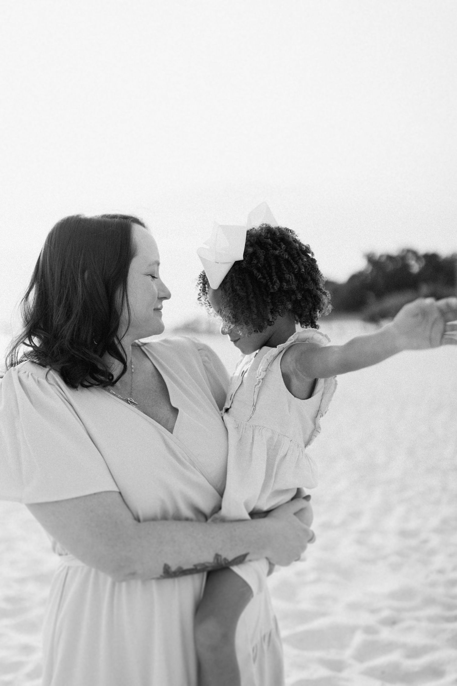 Black and white photo capturing joyful embraces and playful moments at the beach.
