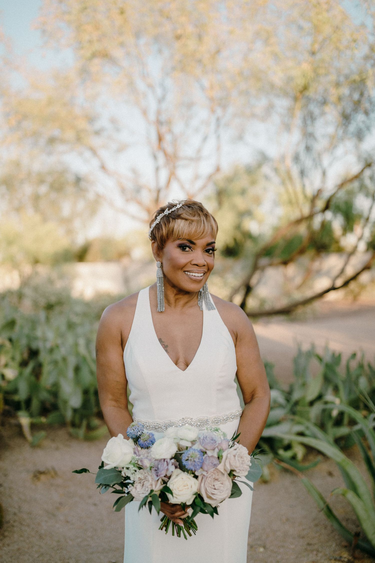 A beautiful bridal portrait series showing a white wedding dress and stunning floral bouquet in a natural outdoor setting.