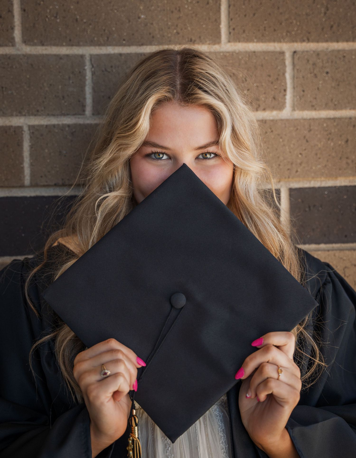 Graduation photo sequence showing playful poses with black cap against brick wall backdrop.