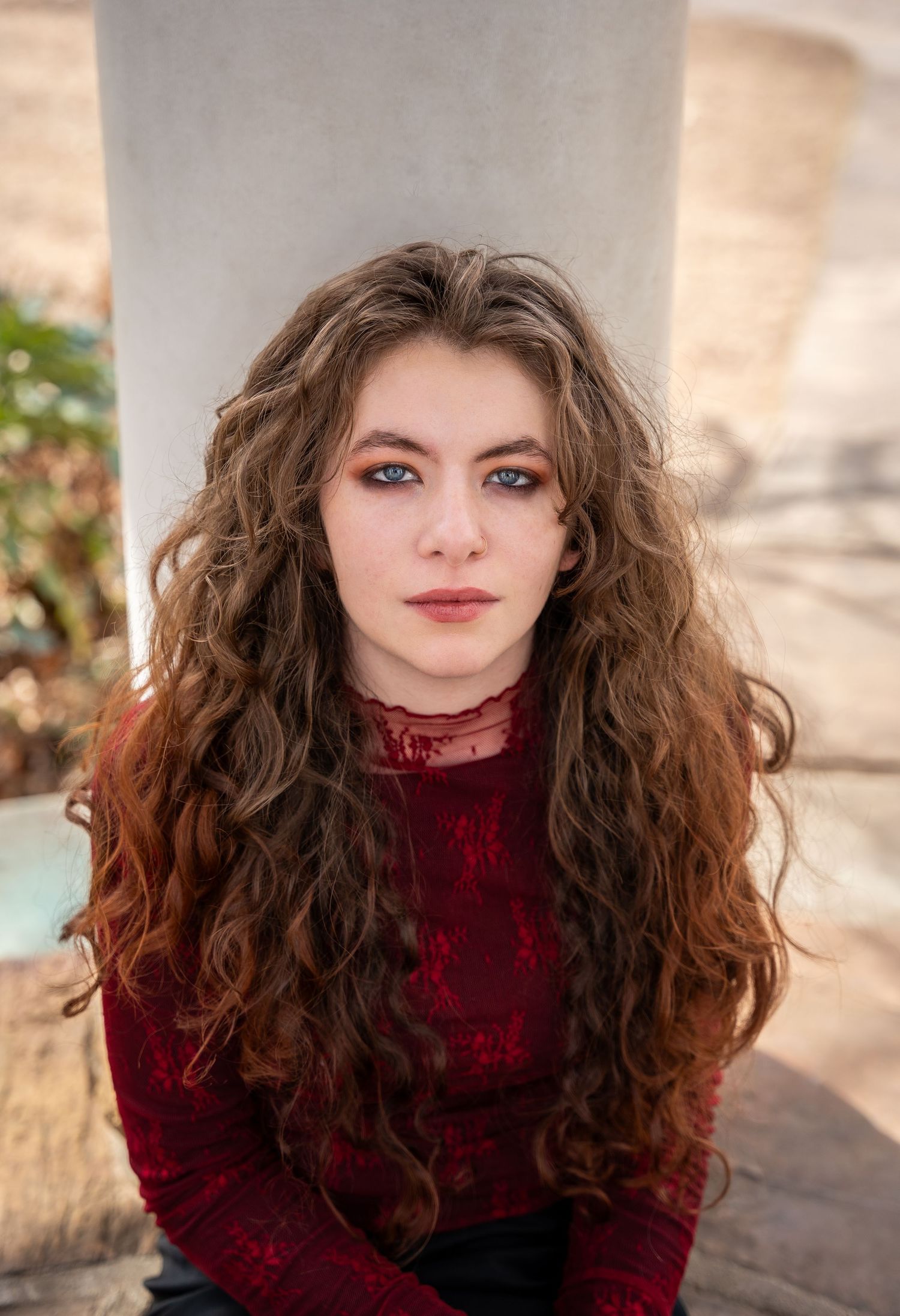 Portrait series in burgundy turtleneck sweater with curly hair against light background.