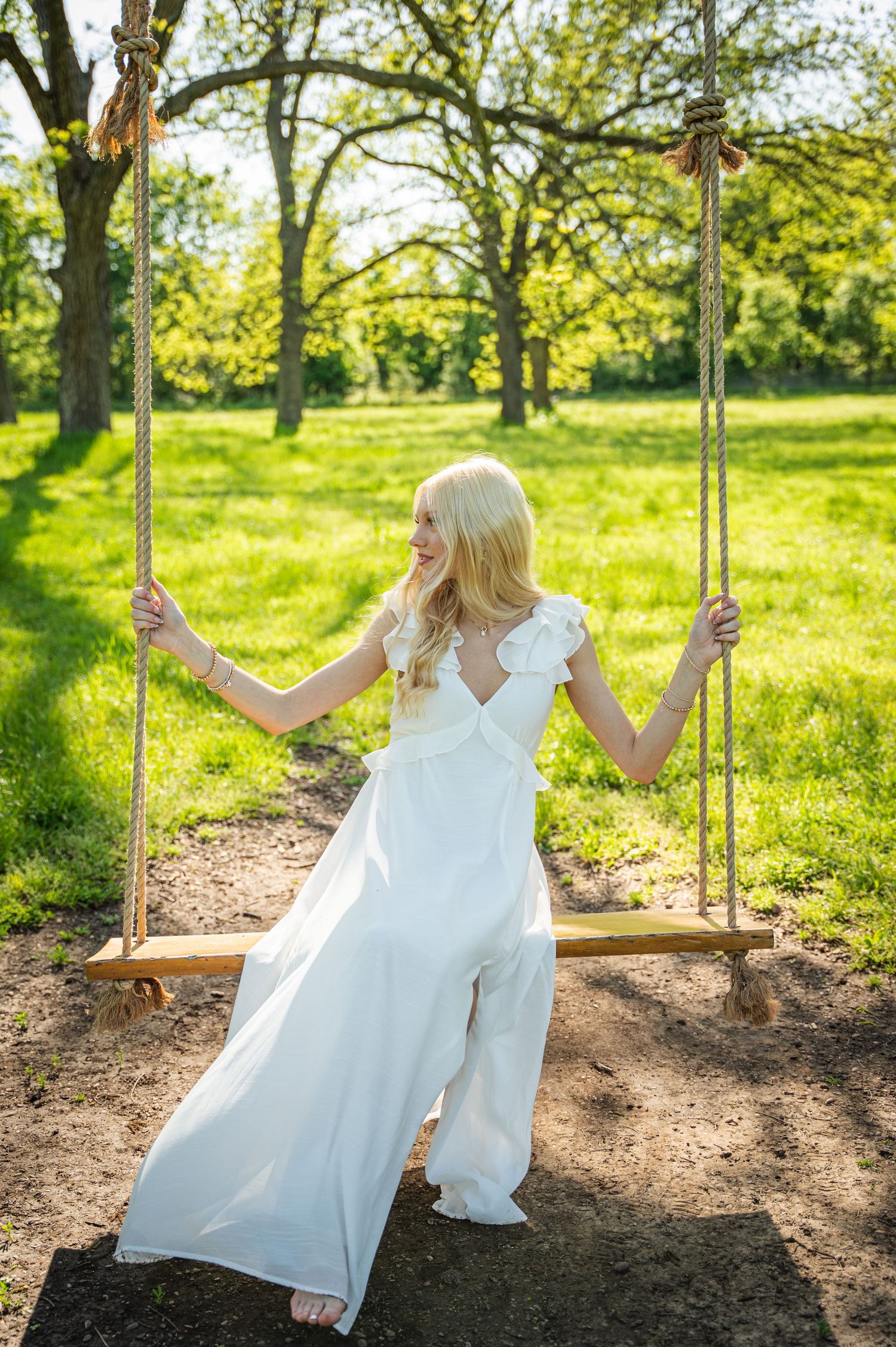 Sequence of someone in white dress swinging joyfully on wooden swing in sunny garden.