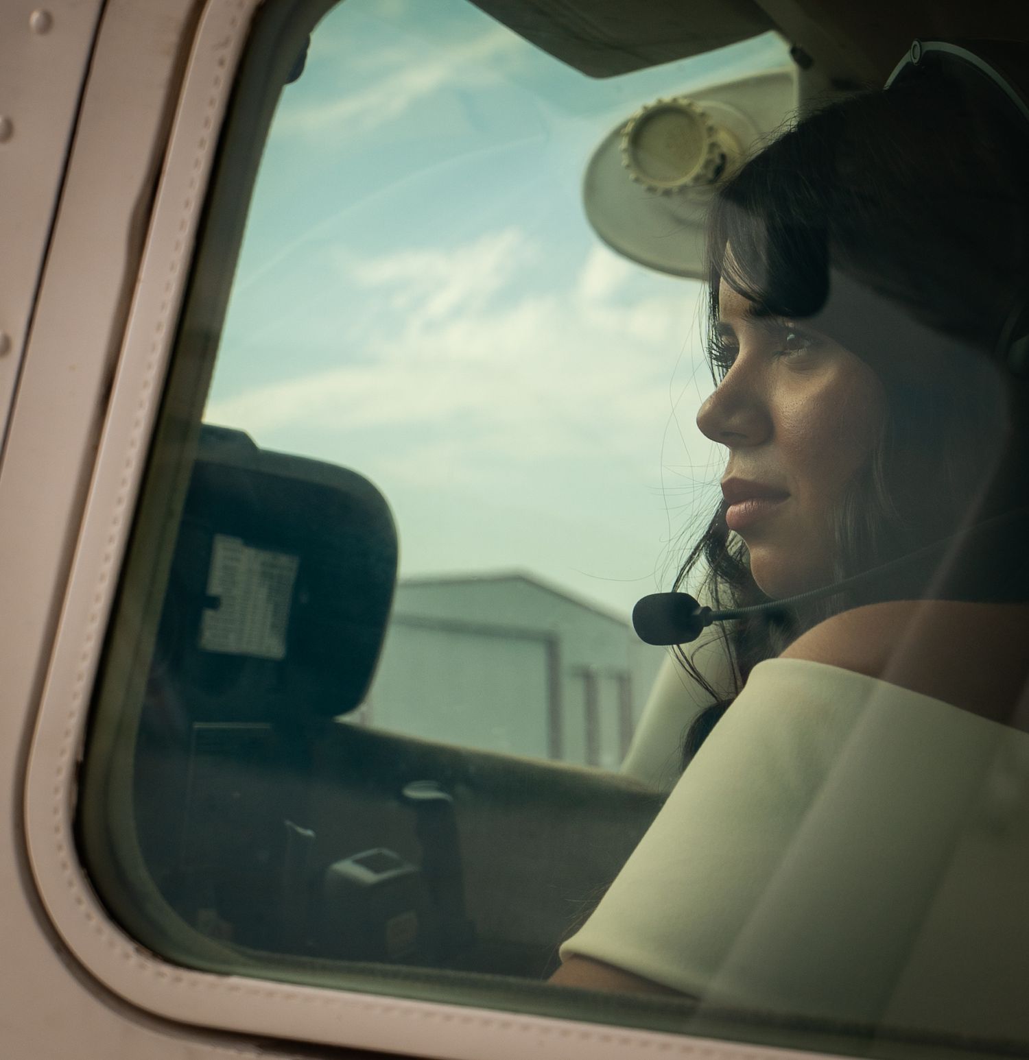 A view through a car window showing a side mirror and road ahead on a calm, cloudy day.