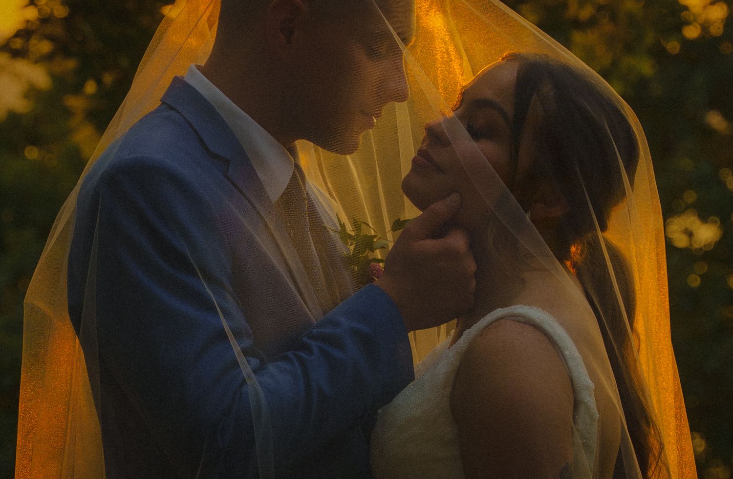 Newlywed couple shares intimate sunset moment in golden hour light during autumn wedding photoshoot.