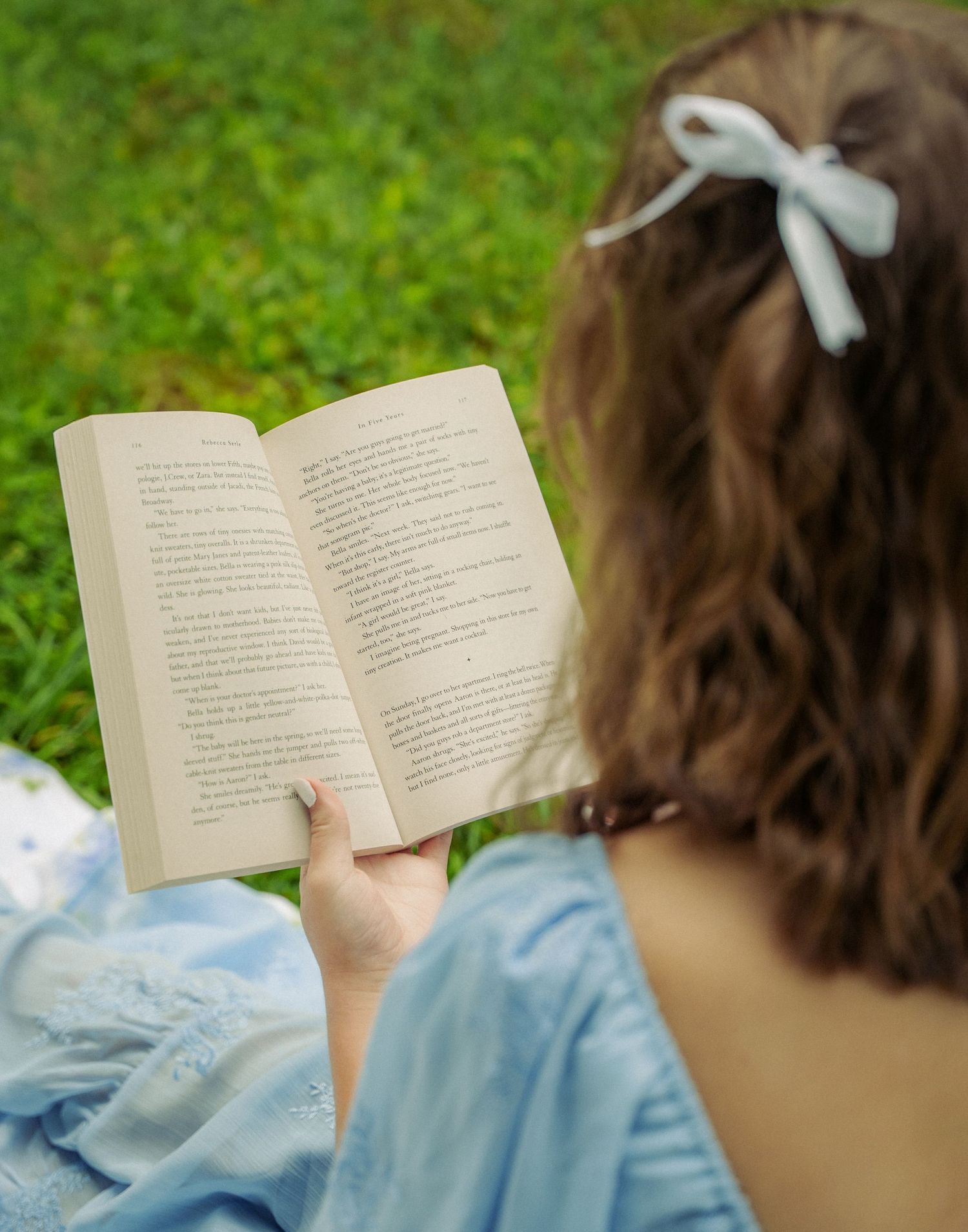 Someone reading a book while lying on the grass in a light blue dress, shown across multiple similar photos.
