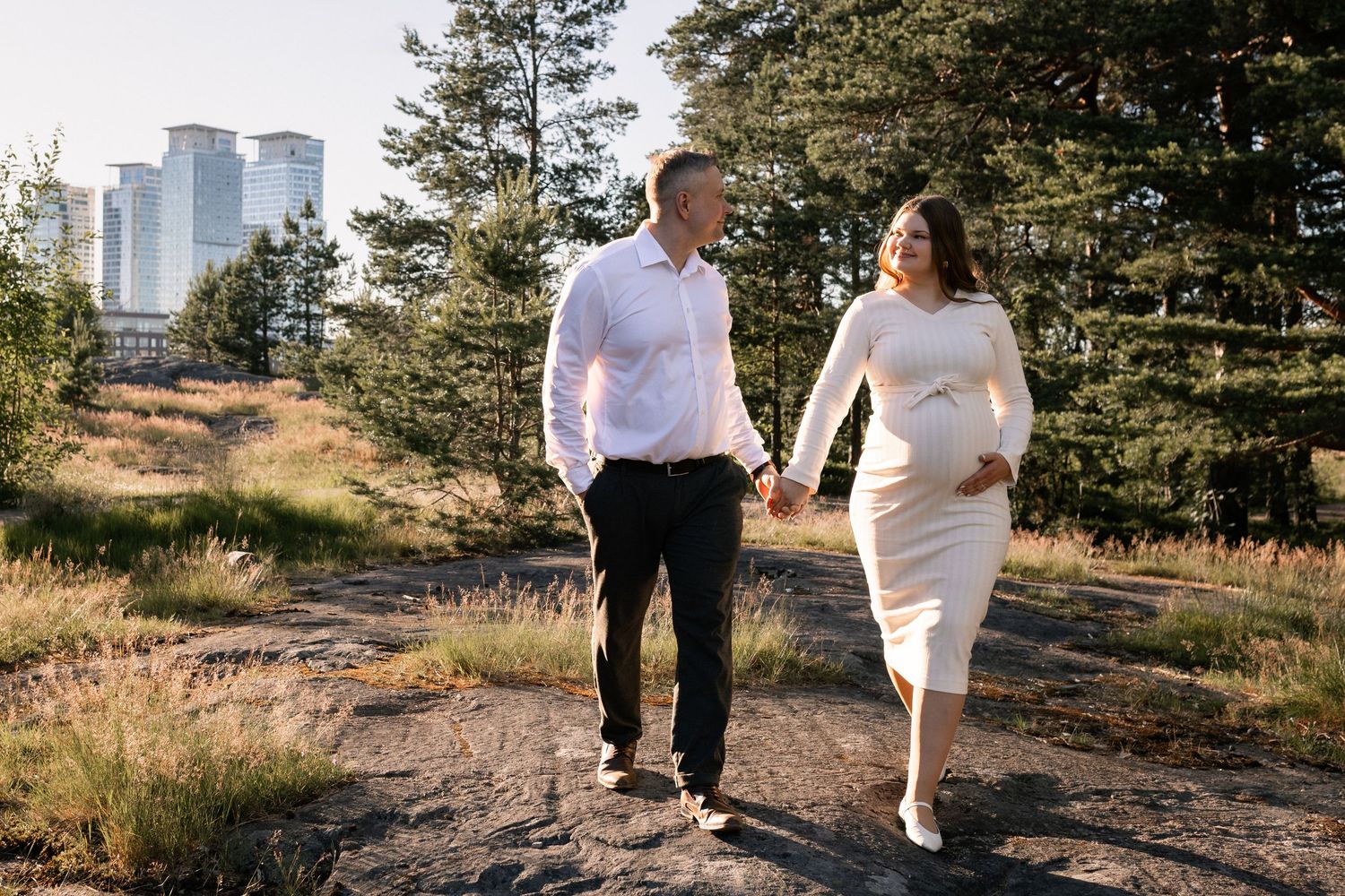 nainen ja mies kävelee käsi kädessä, raskausajan kuvaus miljöössä