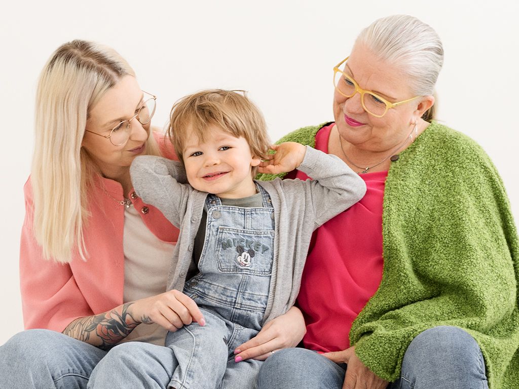 iloinen lapsi valokuvassa äidin ja mummin kanssa
