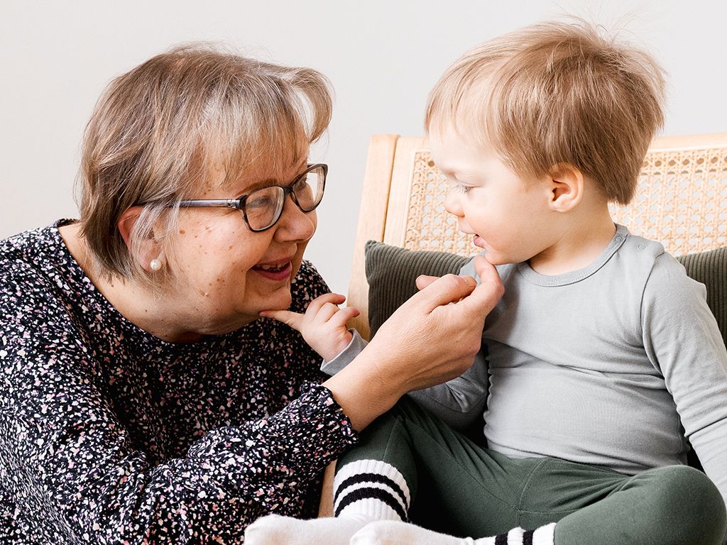 mummo kutittaa lasta leuasta perhekuvauksessa