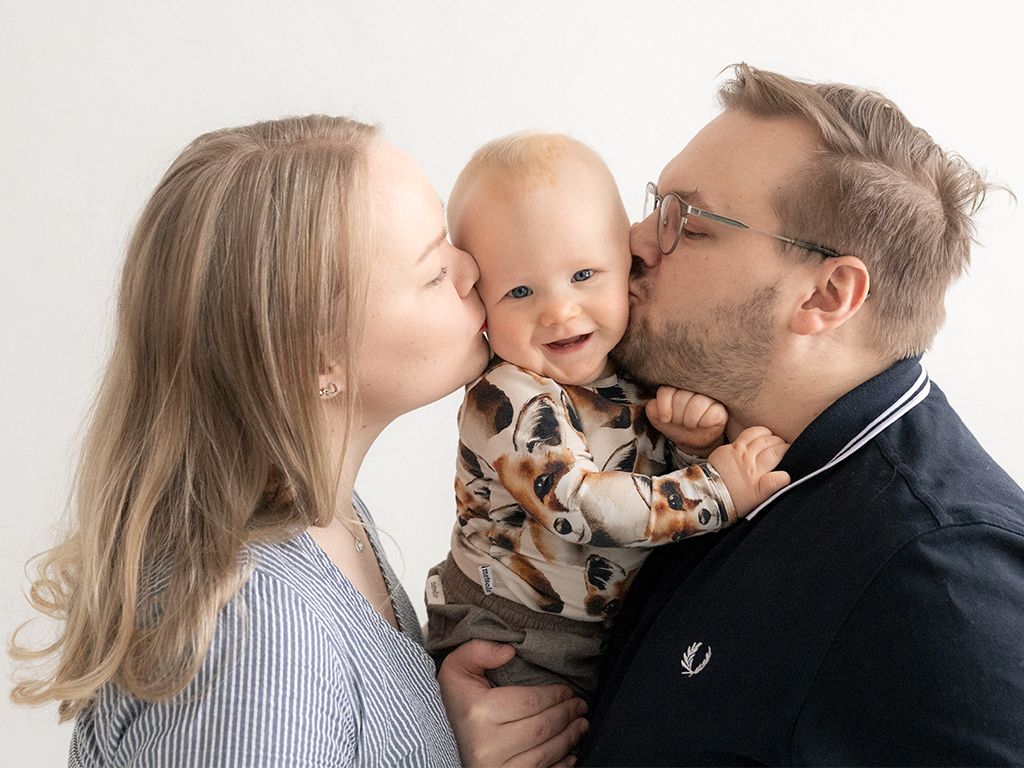 Vauva saa pusun äidiltä ja isältä- perhekuvaus Espoo