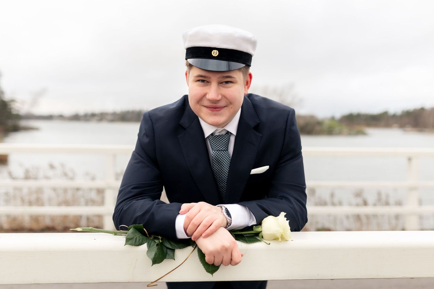 Siltaan nojaava mies- ylioppilaskuvaus miljöössä