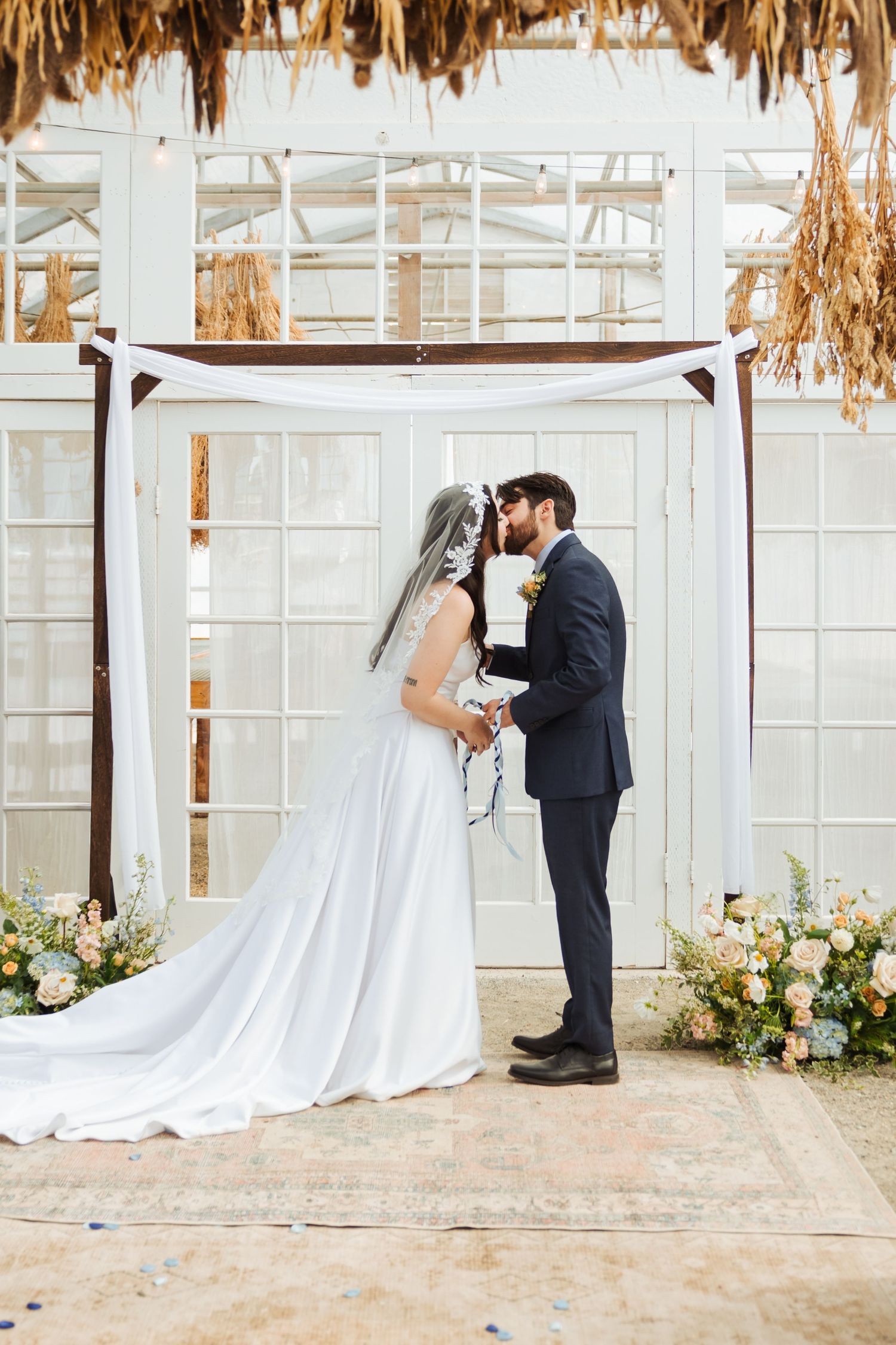 Bride and groom kissing during ceremony at The Kinlands Greenhouse photography by Av Potter Photo a Utah wedding and lifestyle photographer