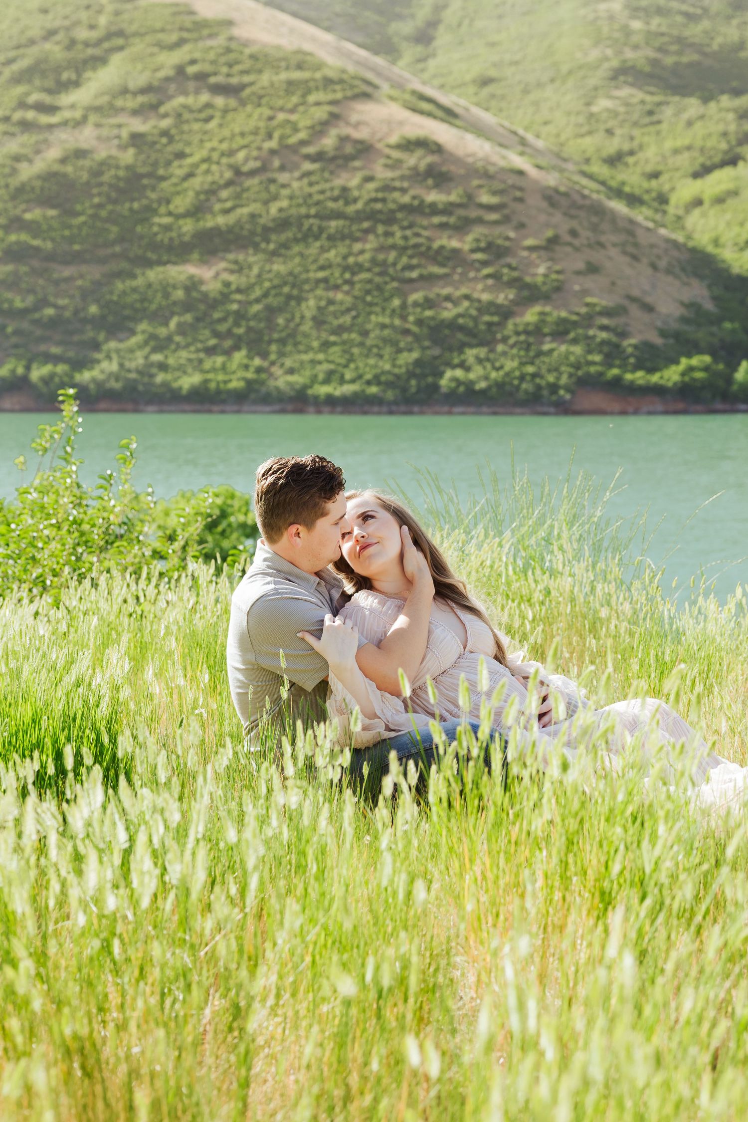 Pregnant woman with husband in field at Little Dell Reservoir photography by Av Potter Photo a Utah wedding and lifestyle photographer