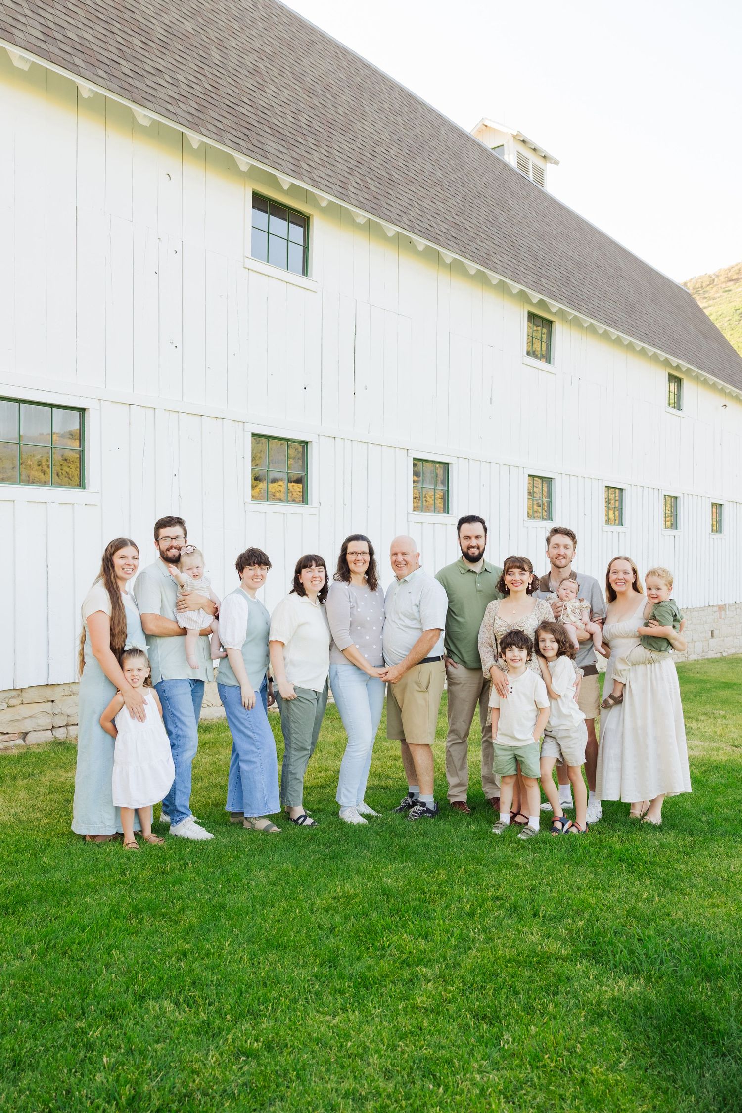 Family in front of white barn at McPolin Barn photography by Av Potter Photo a Utah wedding and lifestyle photographer