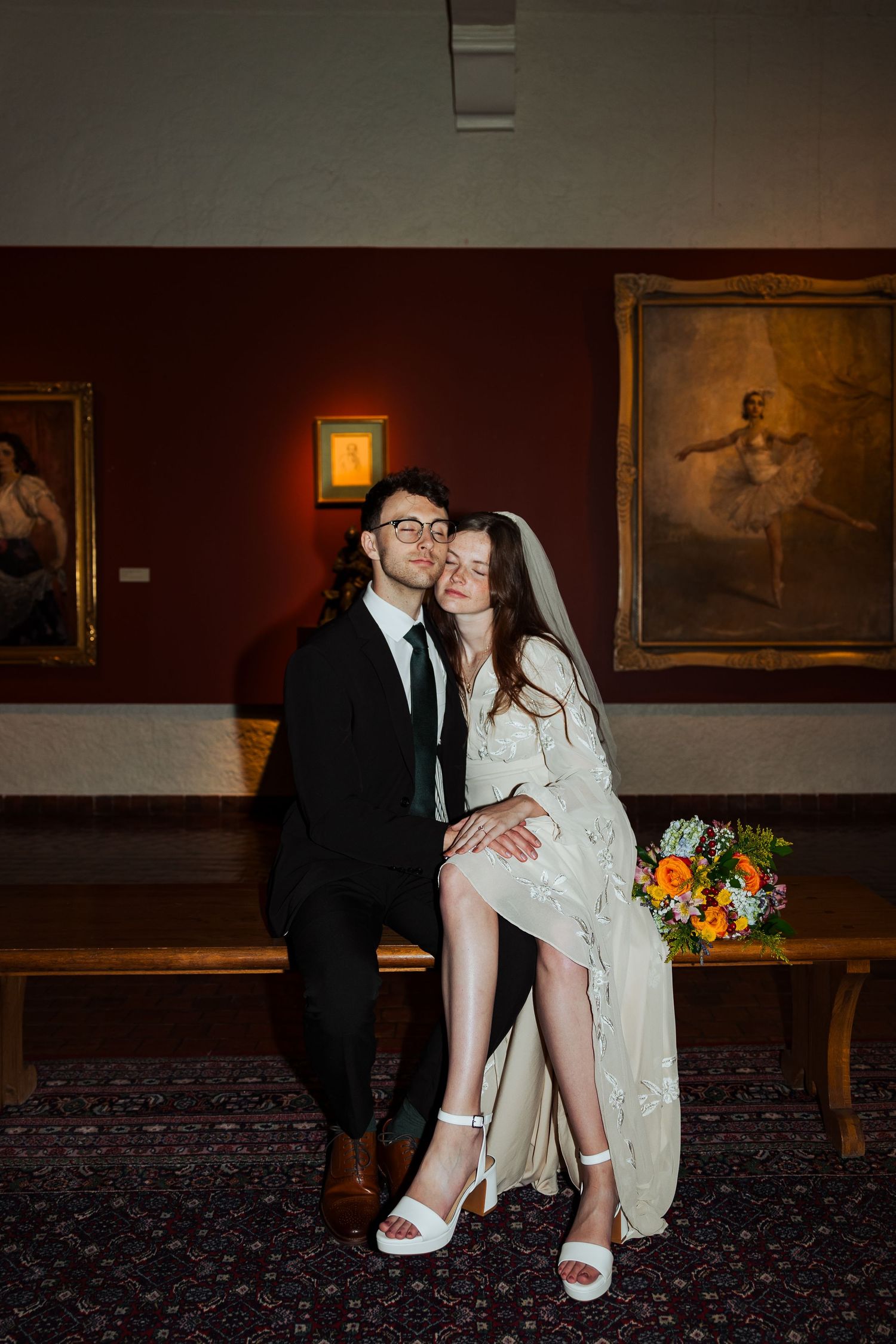 Bride and groom sitting on bench at the Springville Art Museum photography by Av Potter Photo a Utah wedding and lifestyle photographer