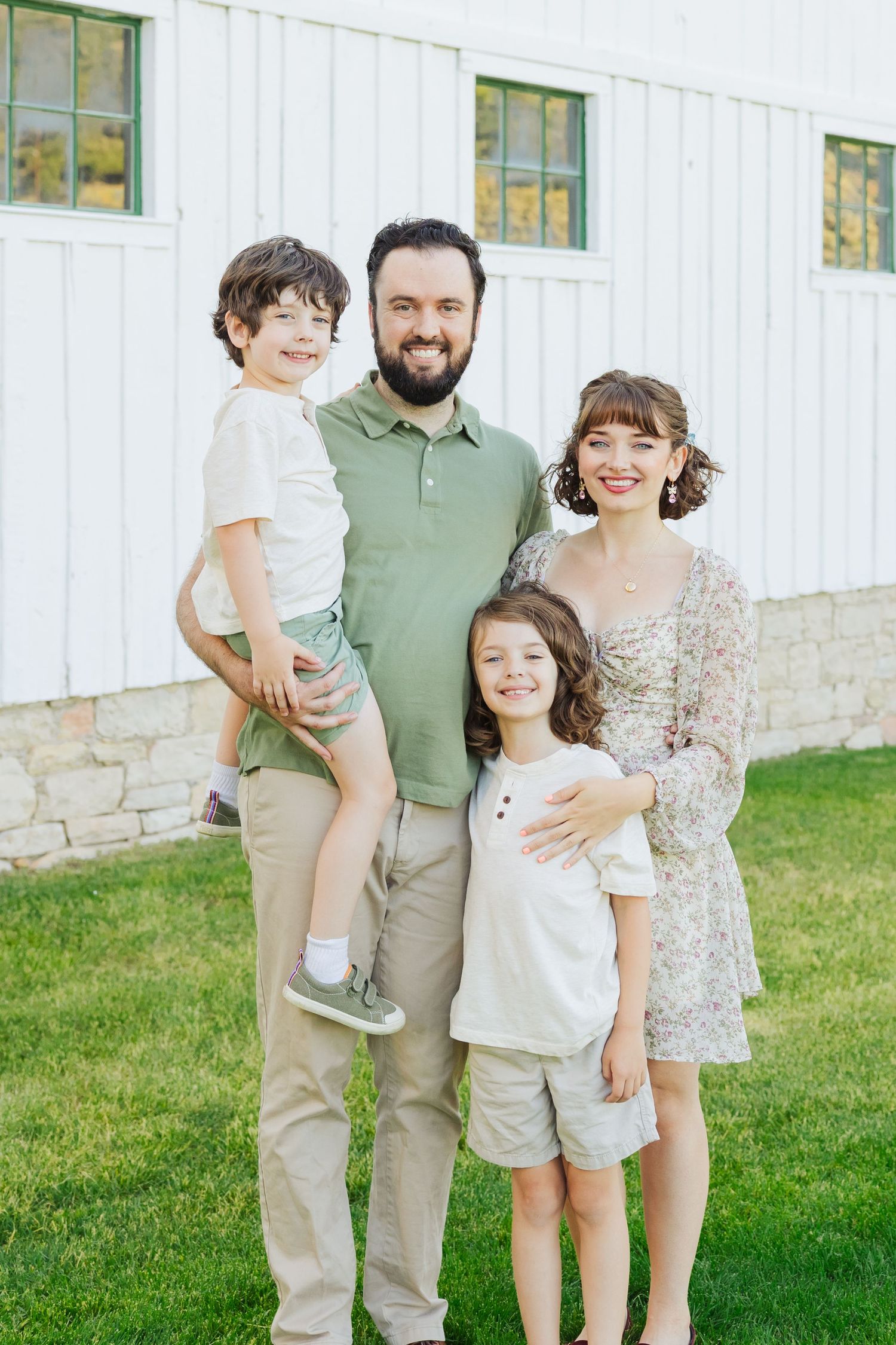 Family in front of white barn at McPolin Barn photography by Av Potter Photo a Utah wedding and lifestyle photographer