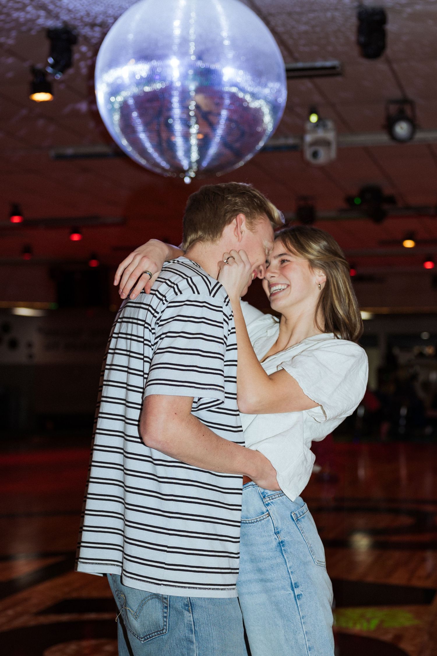 Couple under disco ball at Classic Skating in Orem photography by Av Potter Photo a Utah wedding and lifestyle photographer