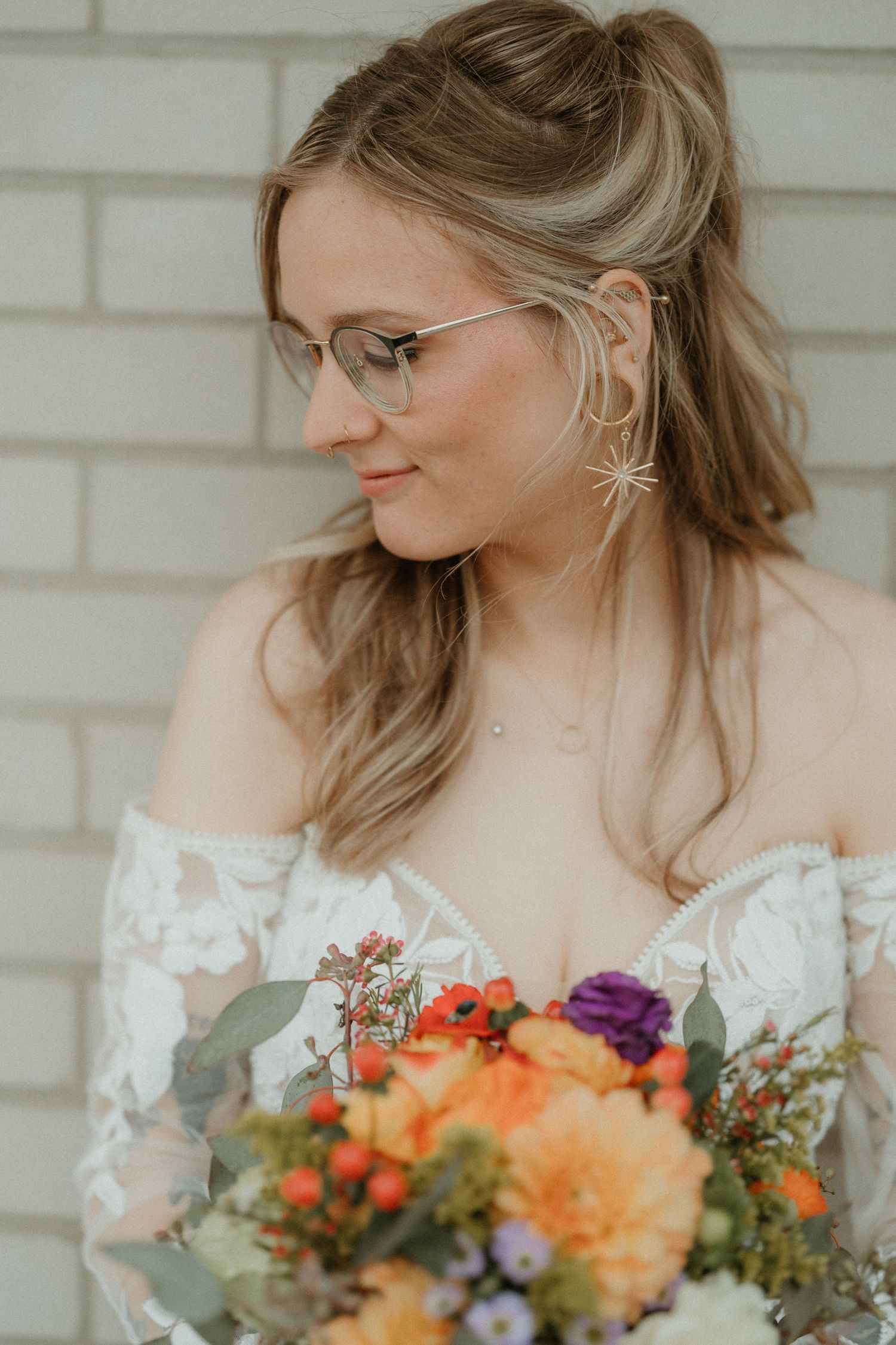 A bridal portrait featuring an off-shoulder lace dress and colorful autumn bouquet.