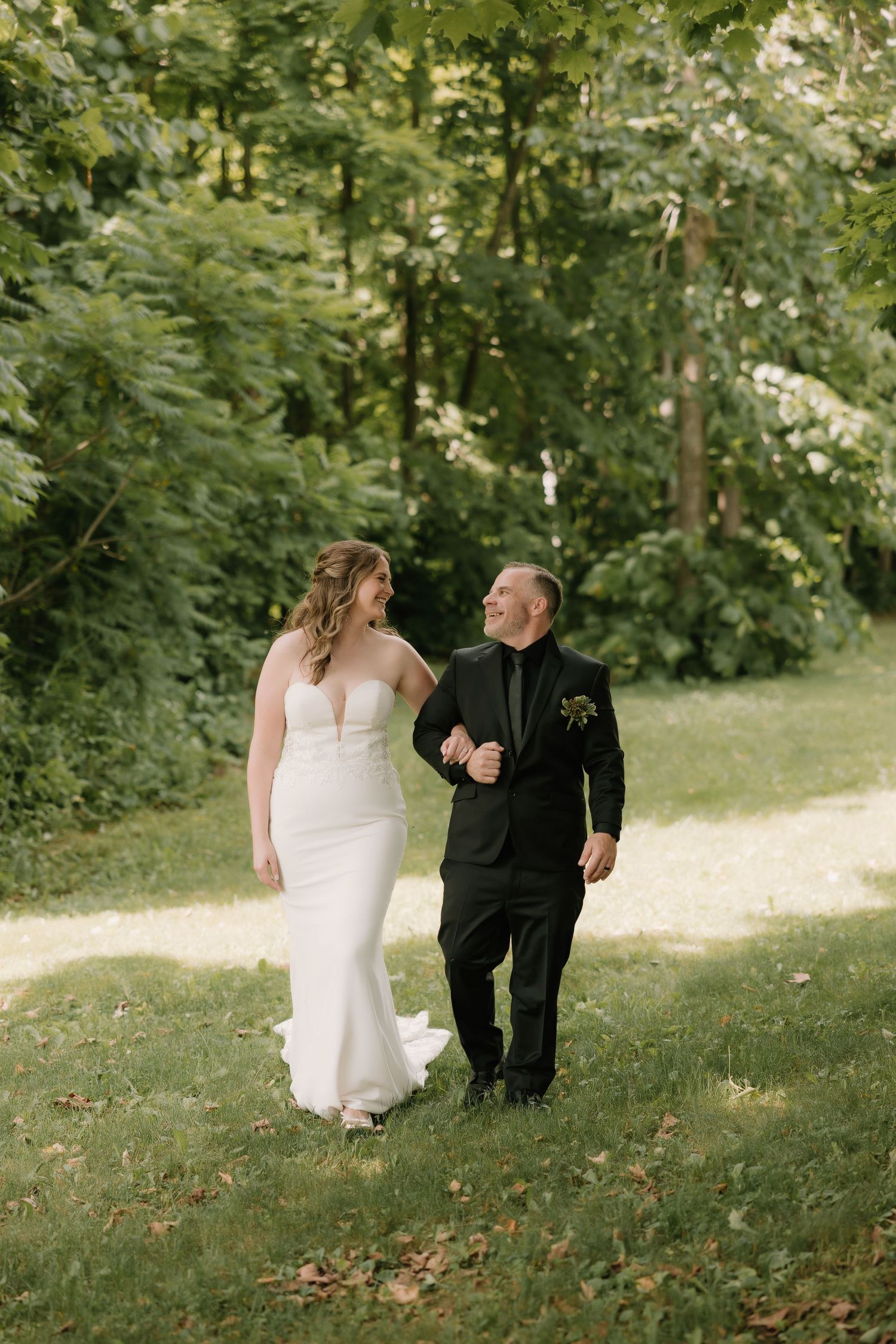 A couple walks hand in hand along a garden path surrounded by lush greenery.