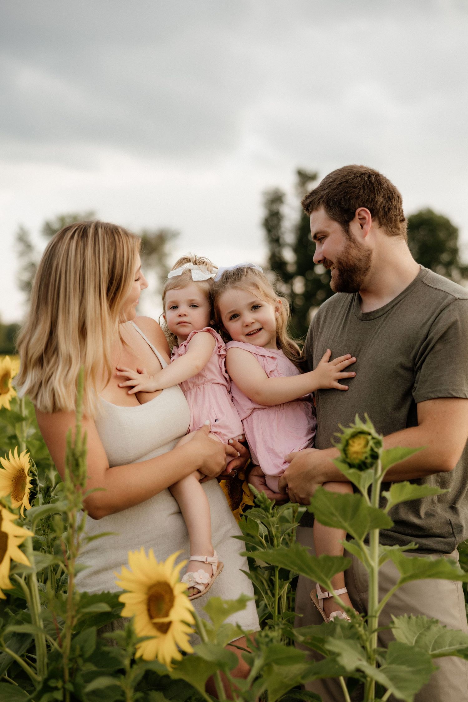 Family enjoying a tender moment together in a sunflower field.