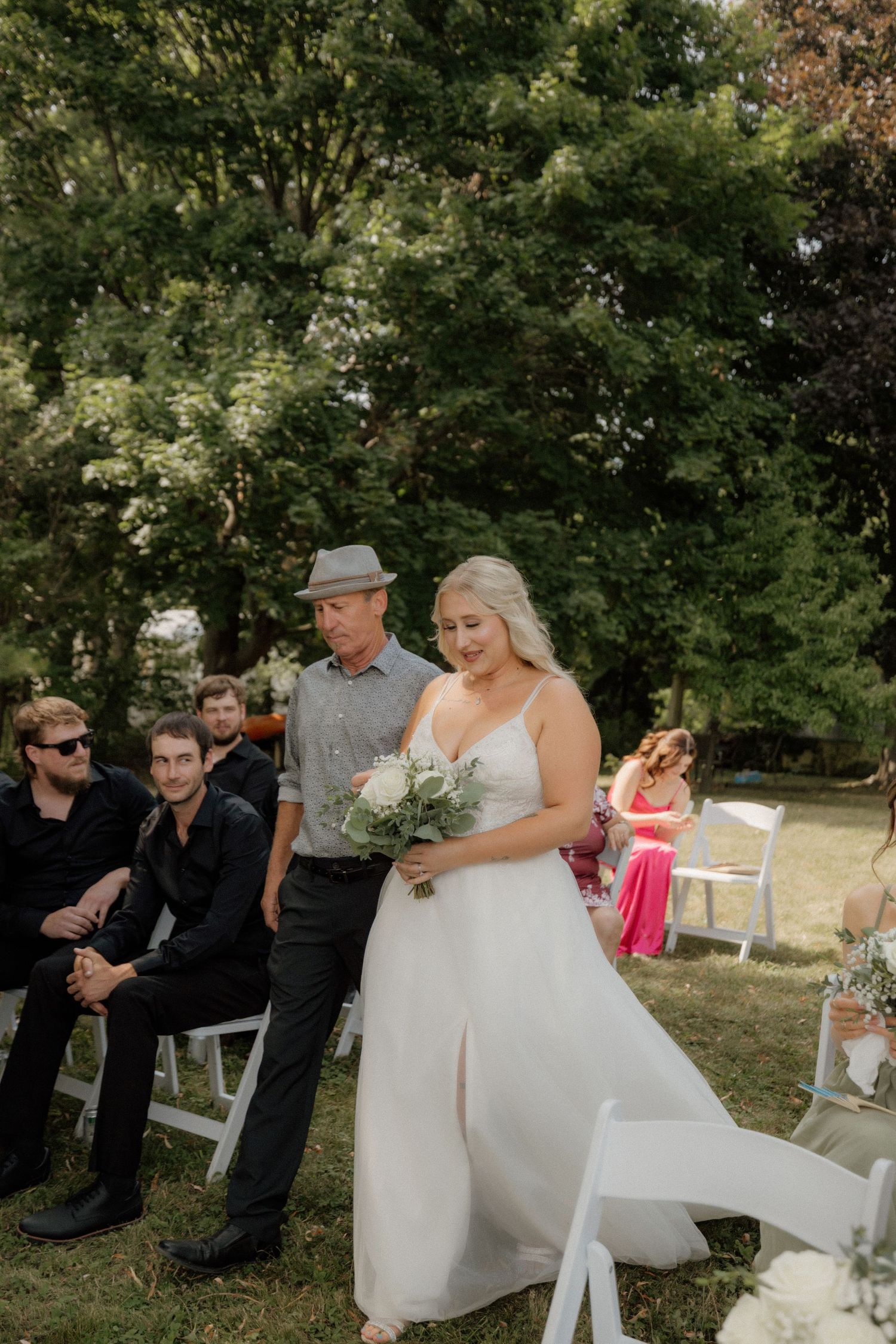 Wedding ceremony setup in outdoor garden setting with white chairs and natural decor.