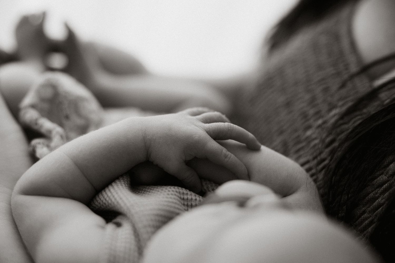 Close-up black and white shot of a tiny baby hand resting gently.