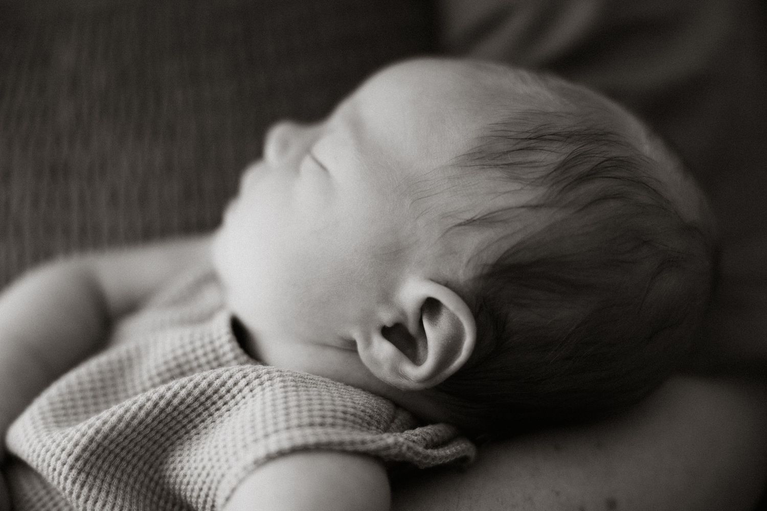 Black and white portrait of sleeping newborn with soft natural lighting.