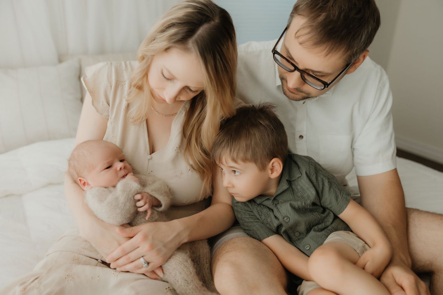 A family sharing a tender moment together on a couch with their baby and young child.