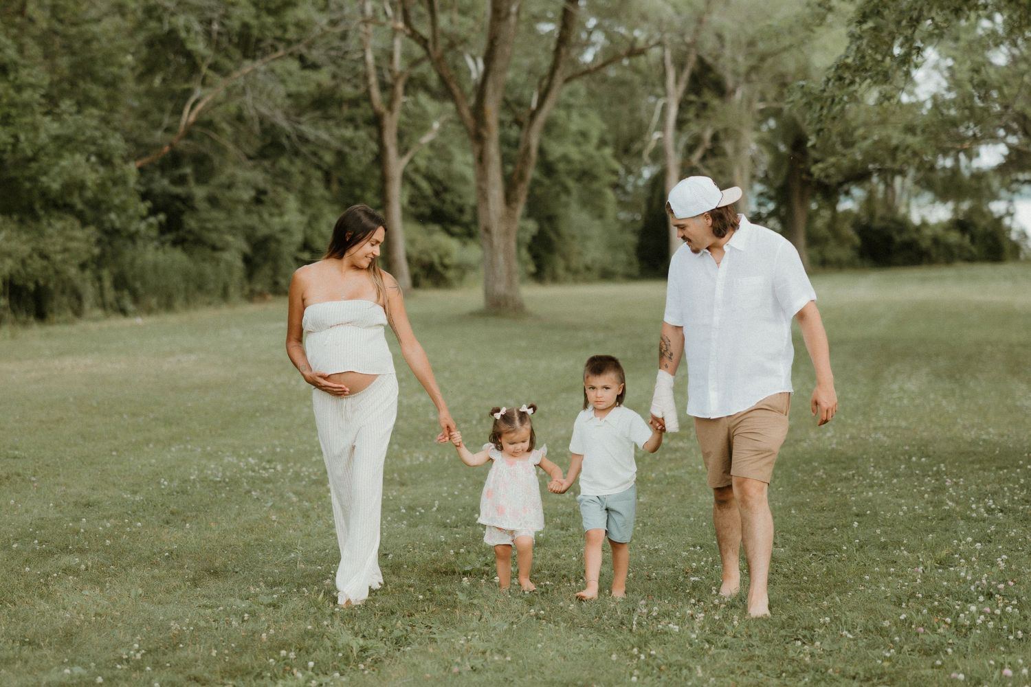 Family walking together on grassy path during summer photoshoot.
