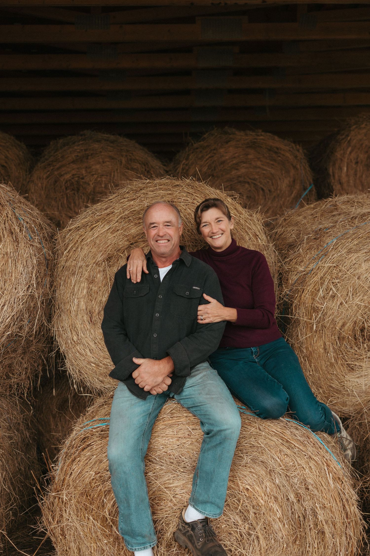 A casual portrait against hay bales wearing burgundy sweater and denim.
