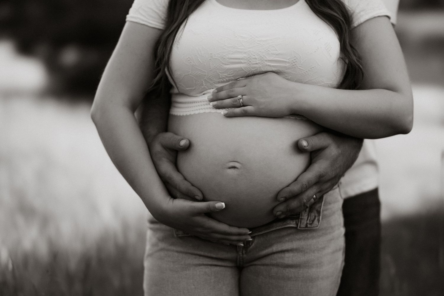 Black and white close-up of hands cradling a pregnant belly.