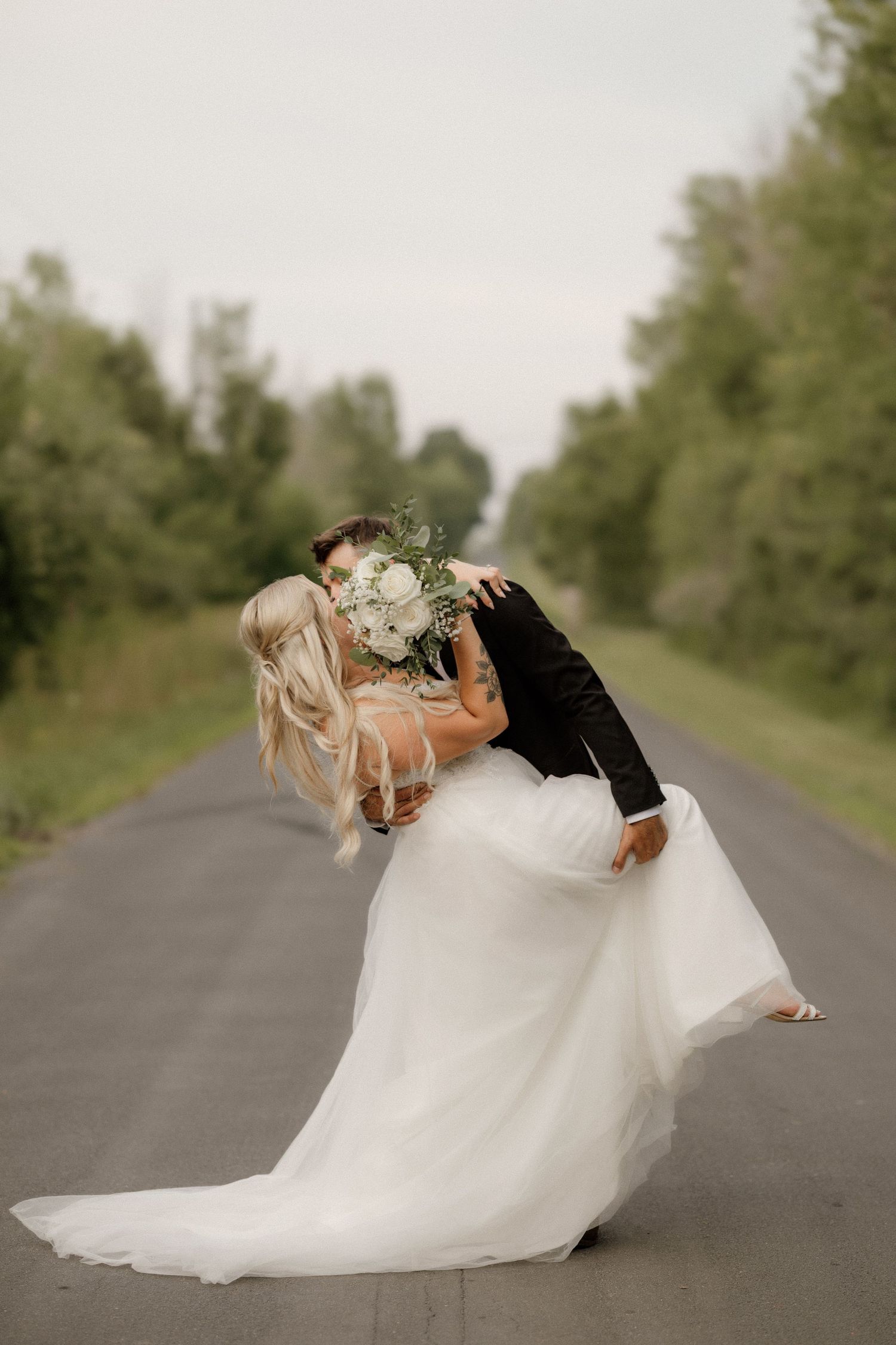 Romantic dip pose during newlywed portrait session on empty country road.