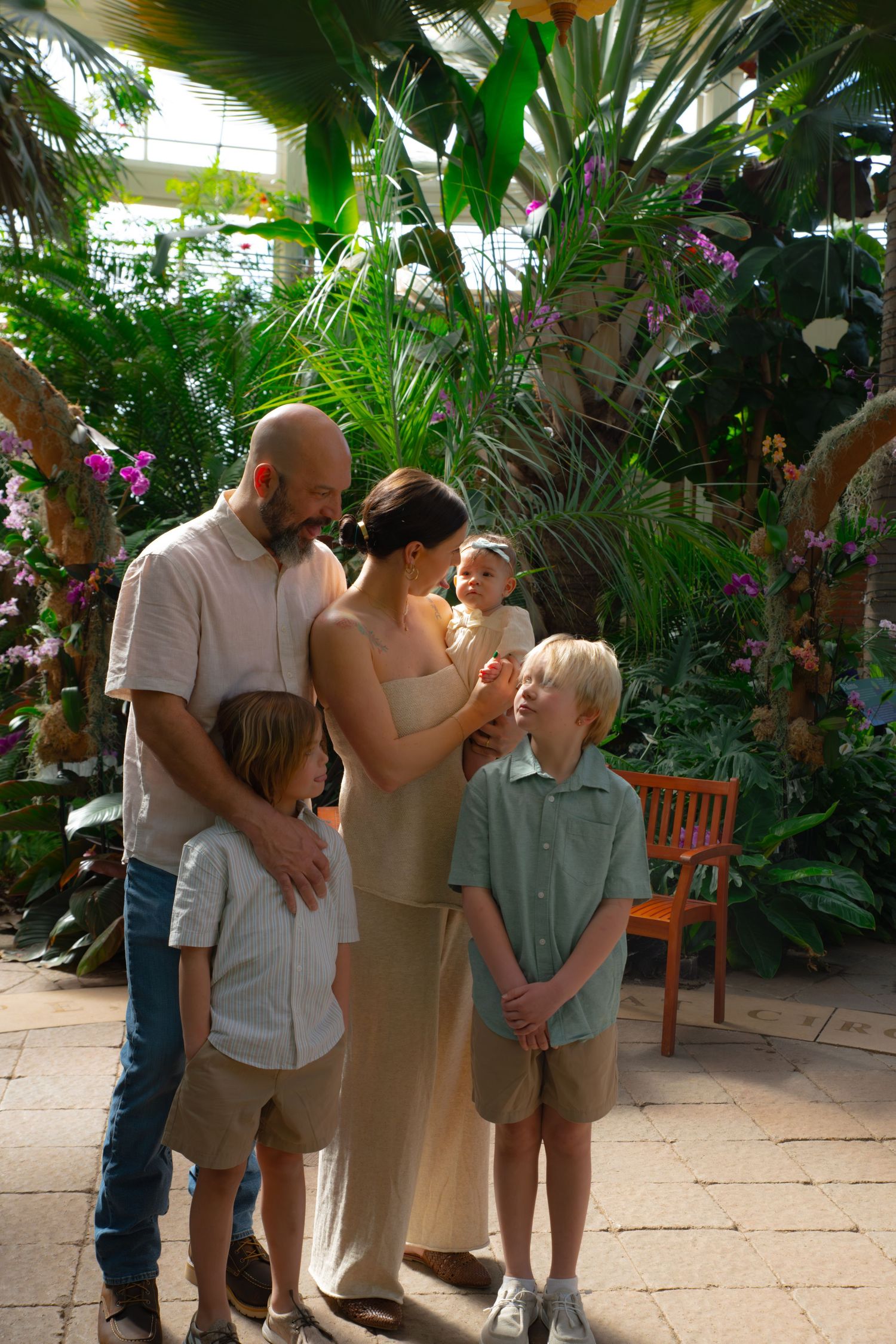 A family gathers for a portrait in a lush tropical garden setting with vibrant plants.
