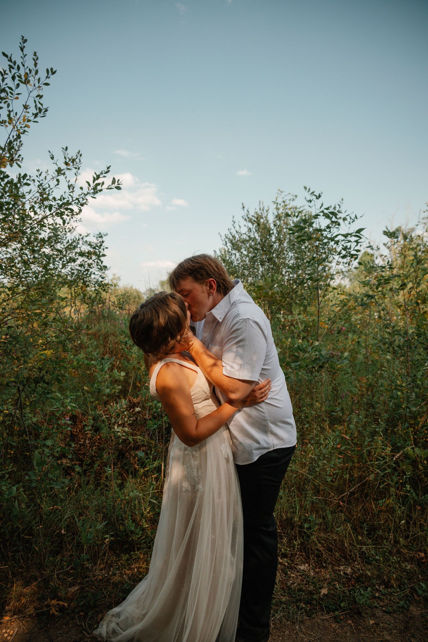 A romantic couple embraces in a garden setting during a tender moment at sunset.