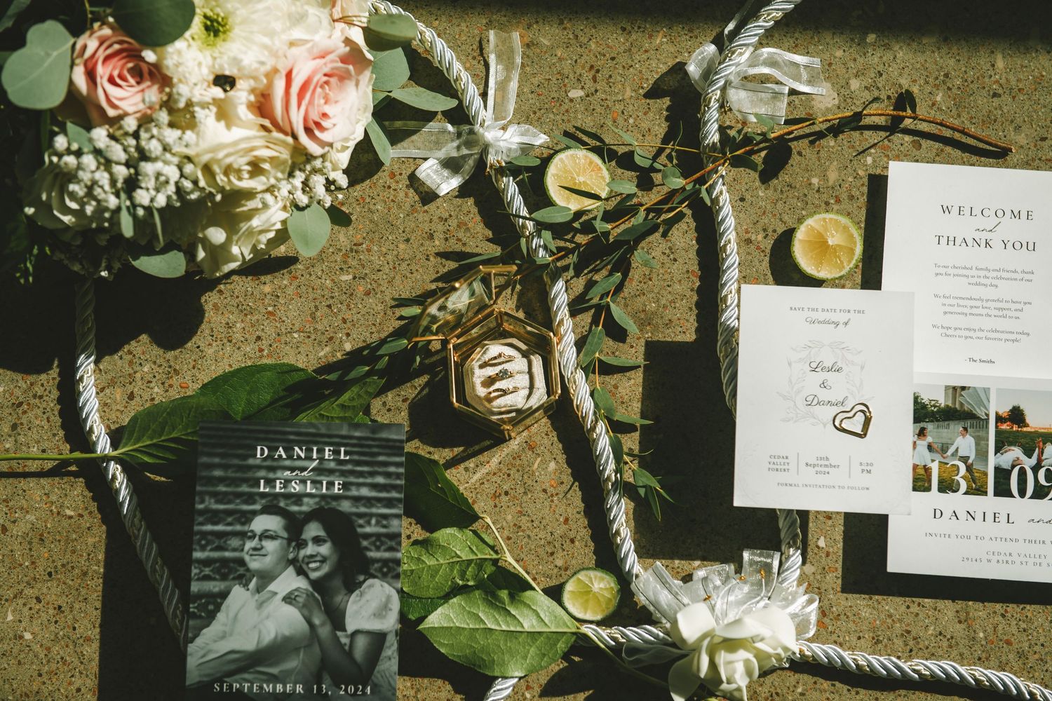 Wedding details including floral arrangements, invitations, and decor elements laid out on a textured surface.