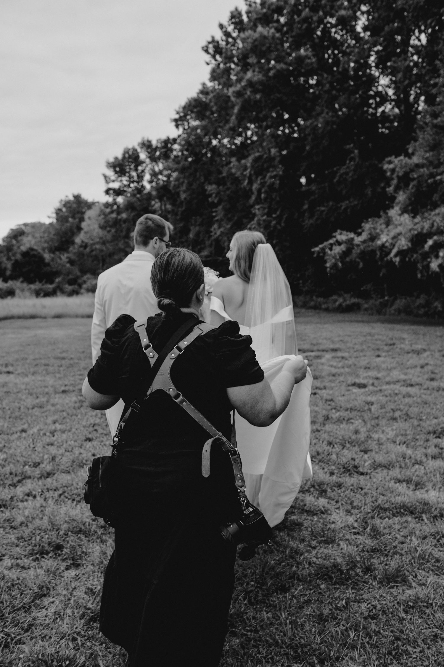 Black and white candid shots of wedding party interactions in an outdoor field setting.