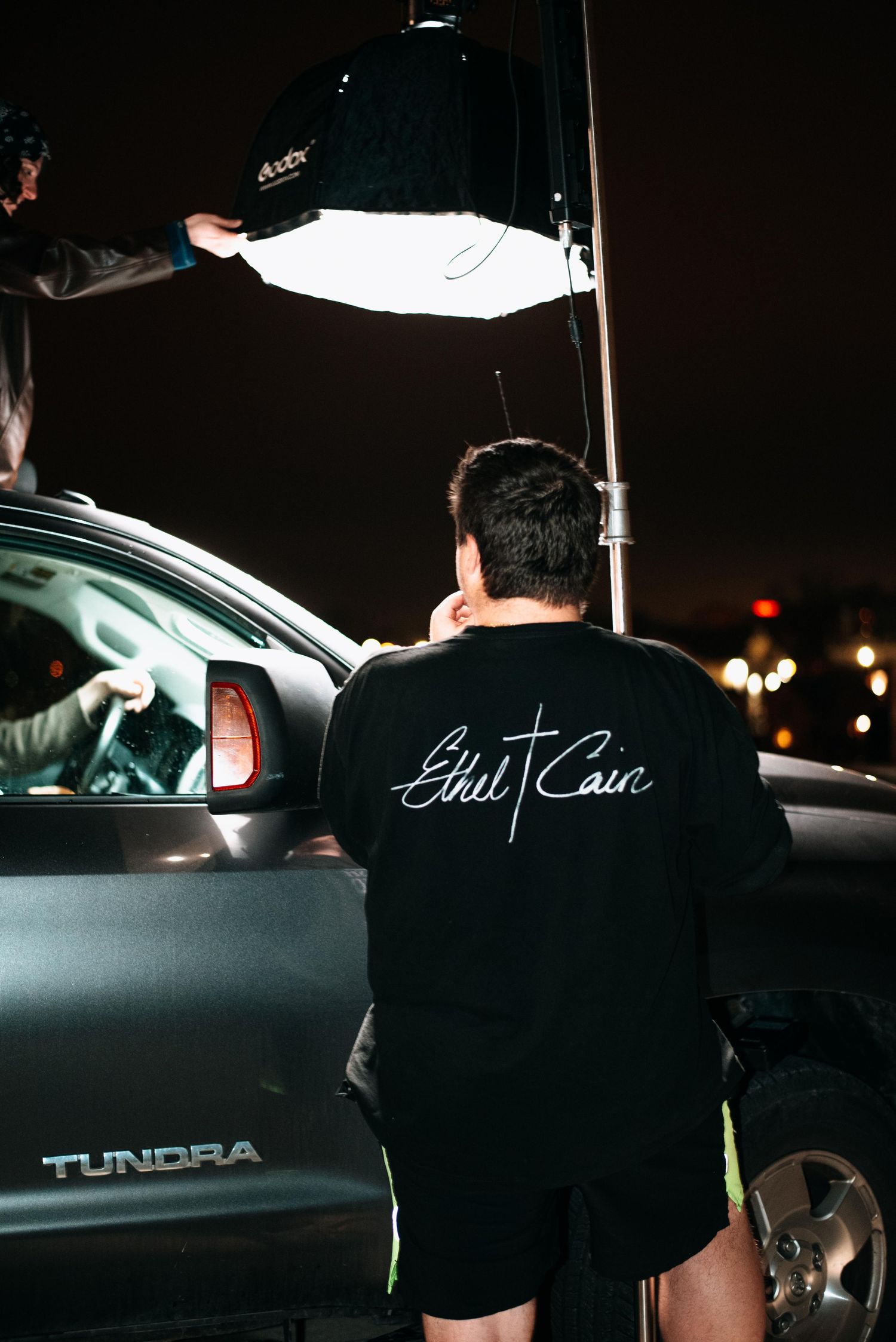 A series of nighttime photos showing a dark Toyota Tundra truck with someone wearing black clothing standing nearby.
