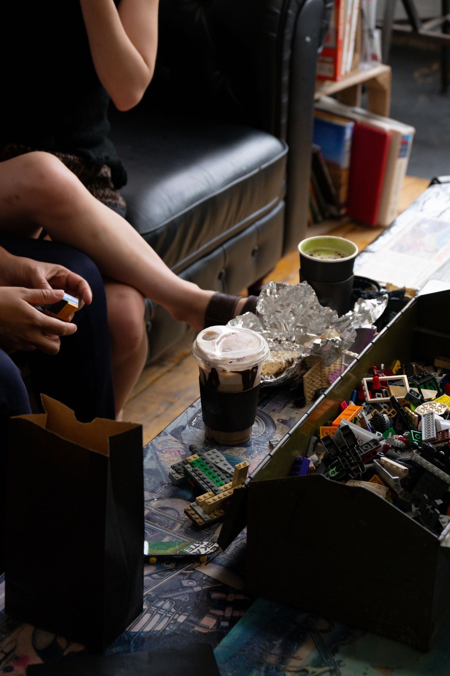 Hands disassembling and repairing electronic components on a dark workbench with tools and parts scattered around.