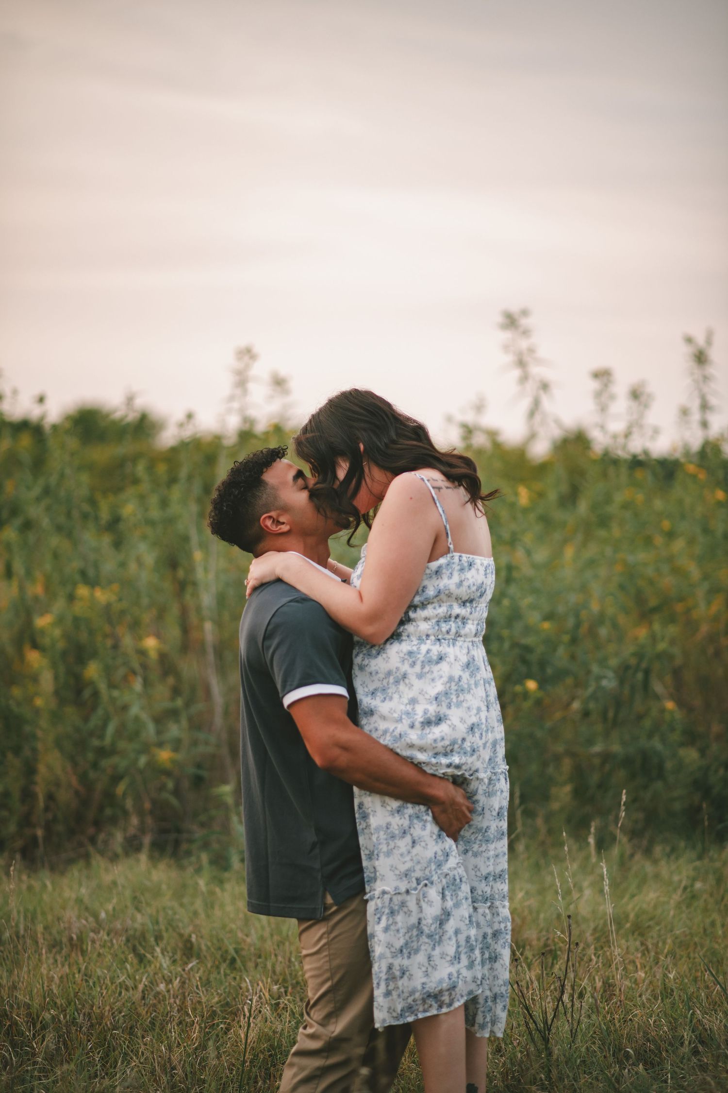 A couple shares a tender embrace in a field of wildflowers during golden hour.