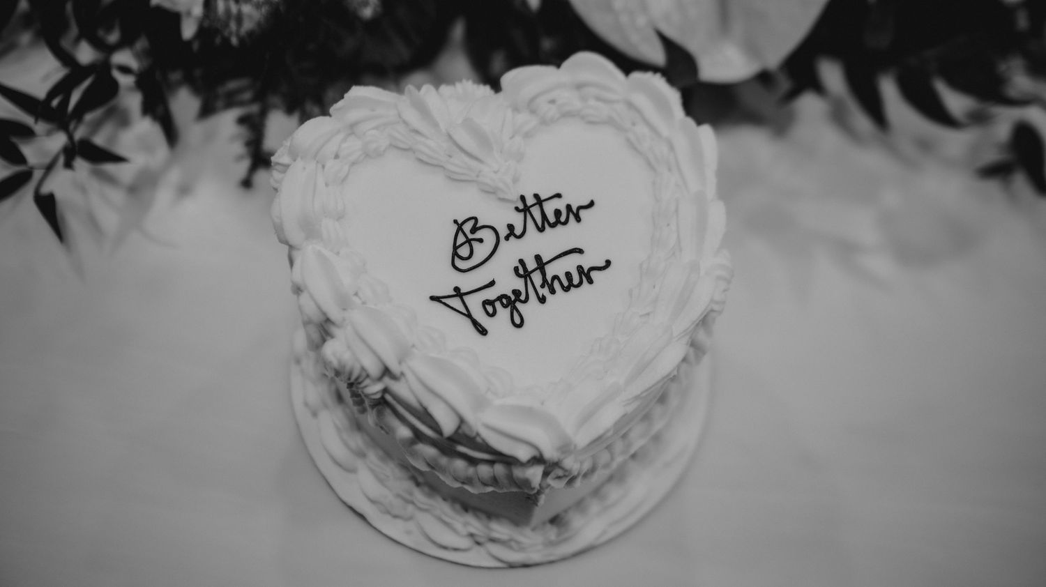 A black and white photo of a heart-shaped wedding cake with handwritten text.