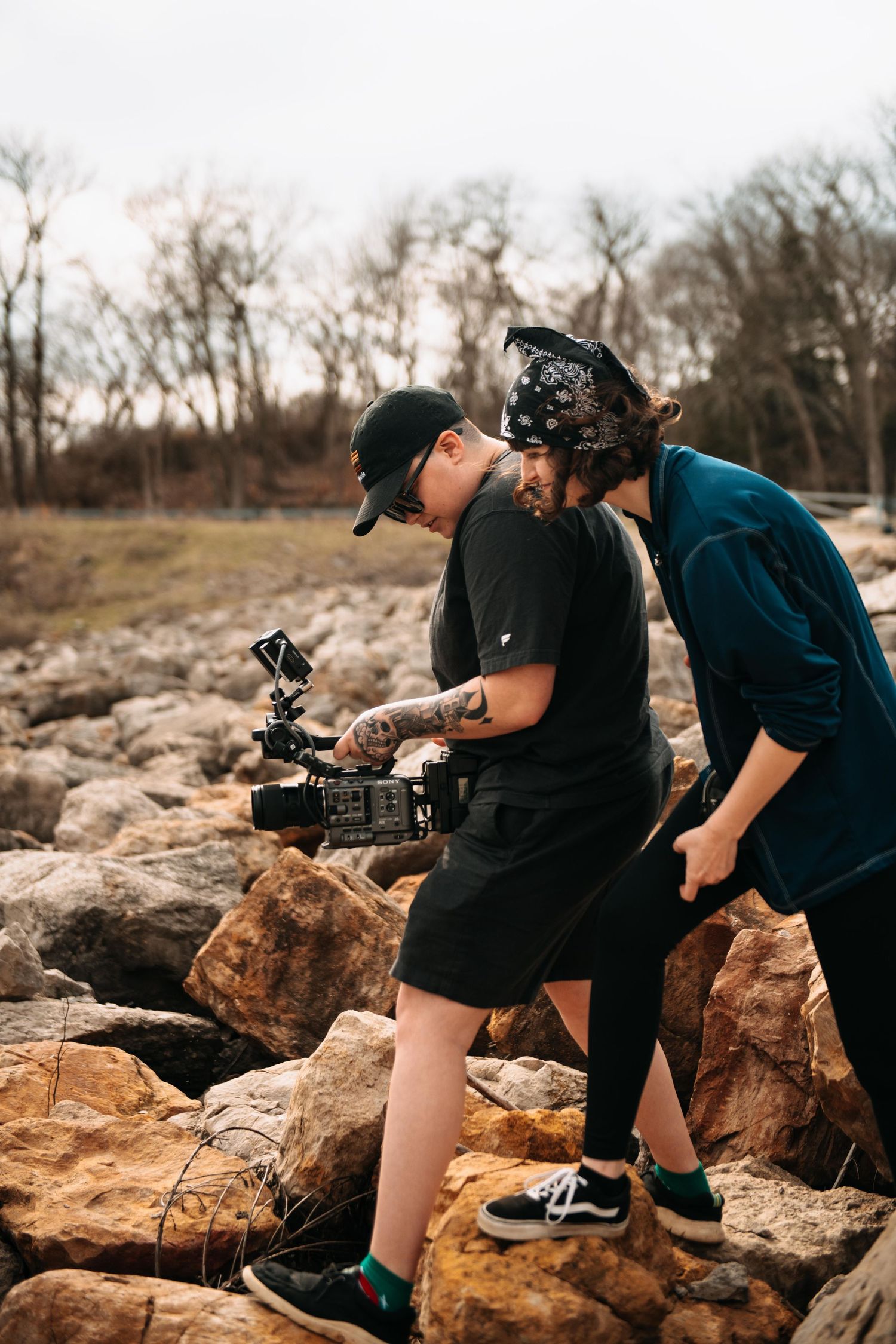 Two photographers in black shirts capture photos on rocky terrain during a nature photoshoot session.