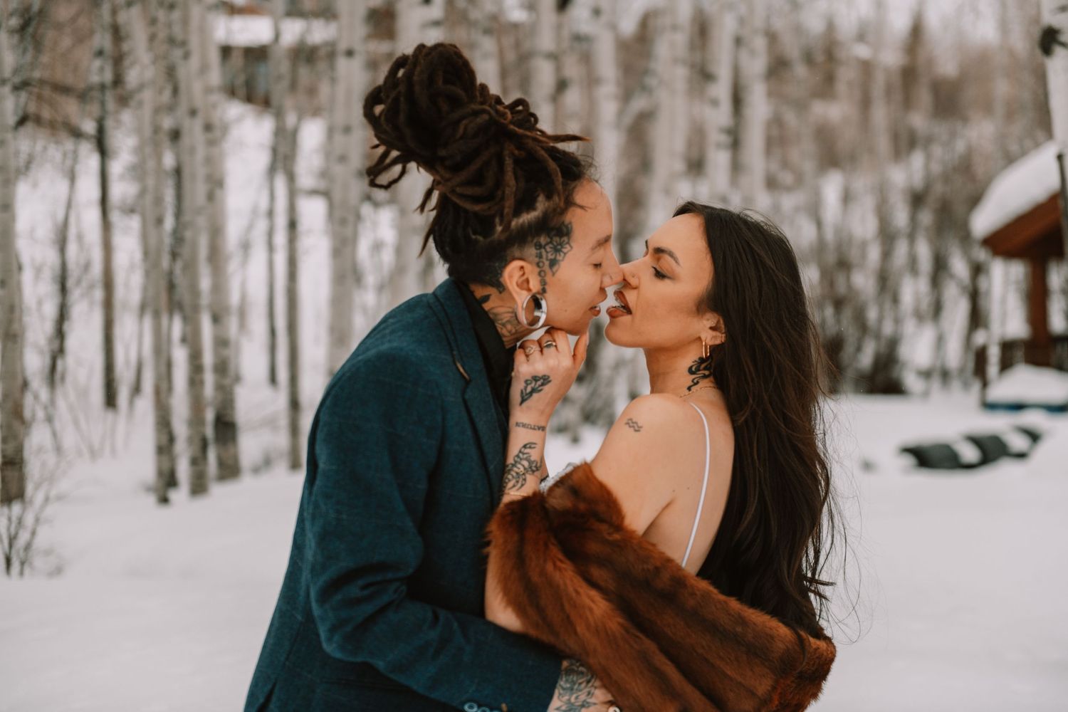 Romantic winter engagement photos in a snowy forest setting with intimate poses and warm winter attire.