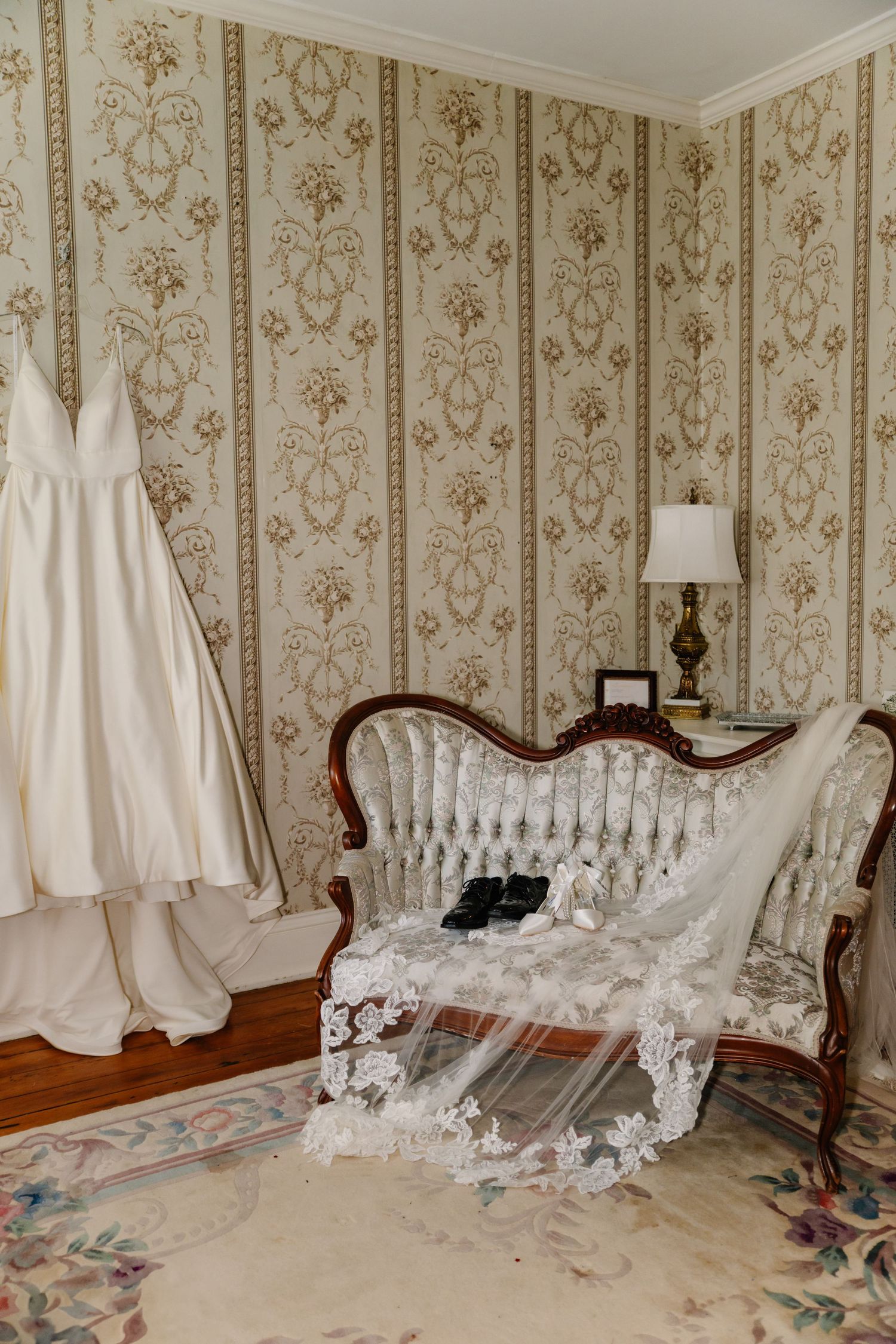 White wedding dresses displayed in a vintage room with ornate wallpaper and antique furniture.
