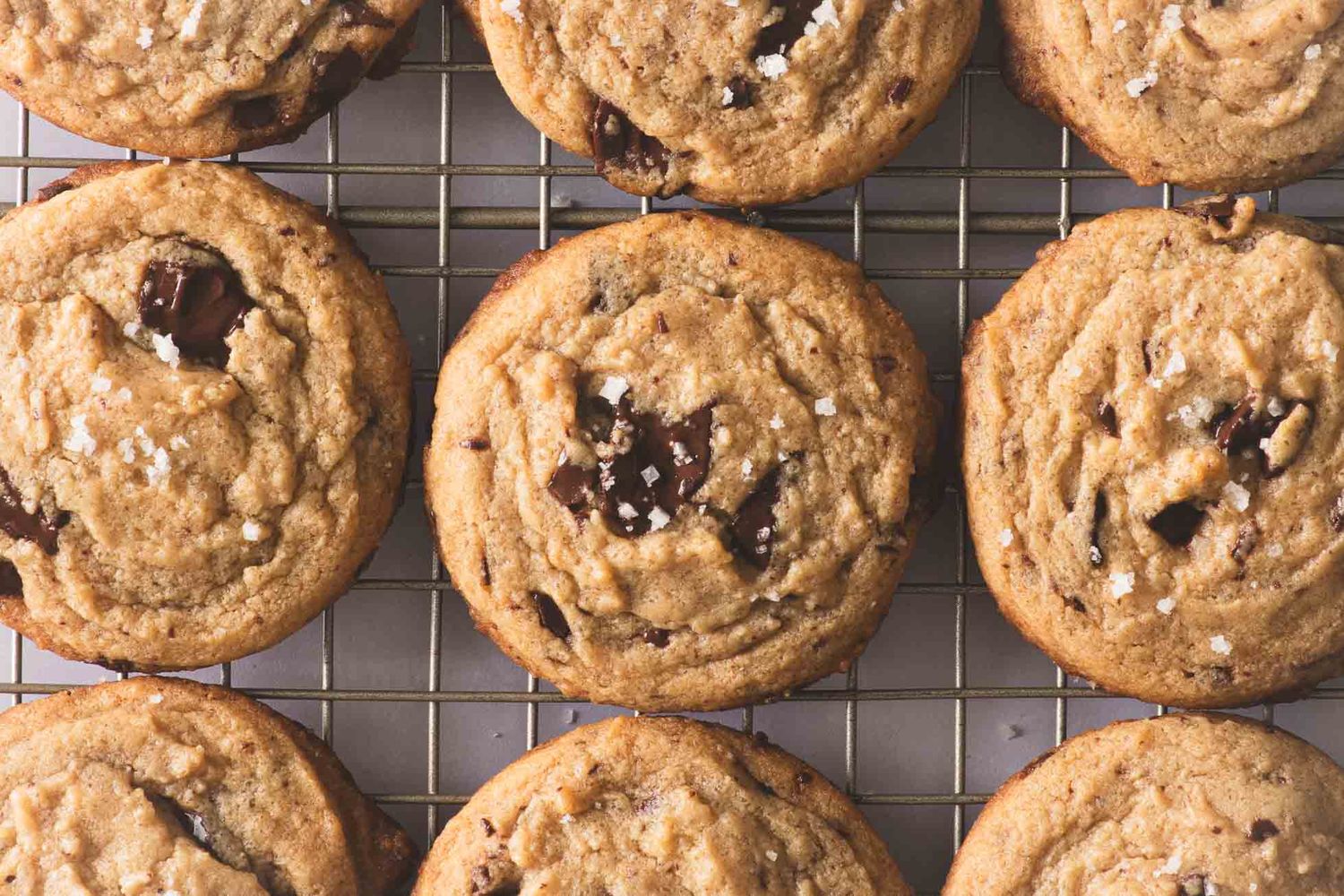 Homemade chocolate chip cookies cooling on a wire baking rack with perfectly melted chocolate chips.