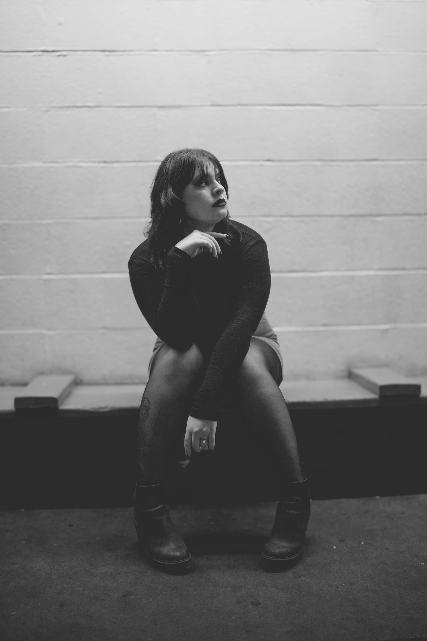 Woman sitting against a wall in a dramatic black and white portrait during a Big Bear photography session