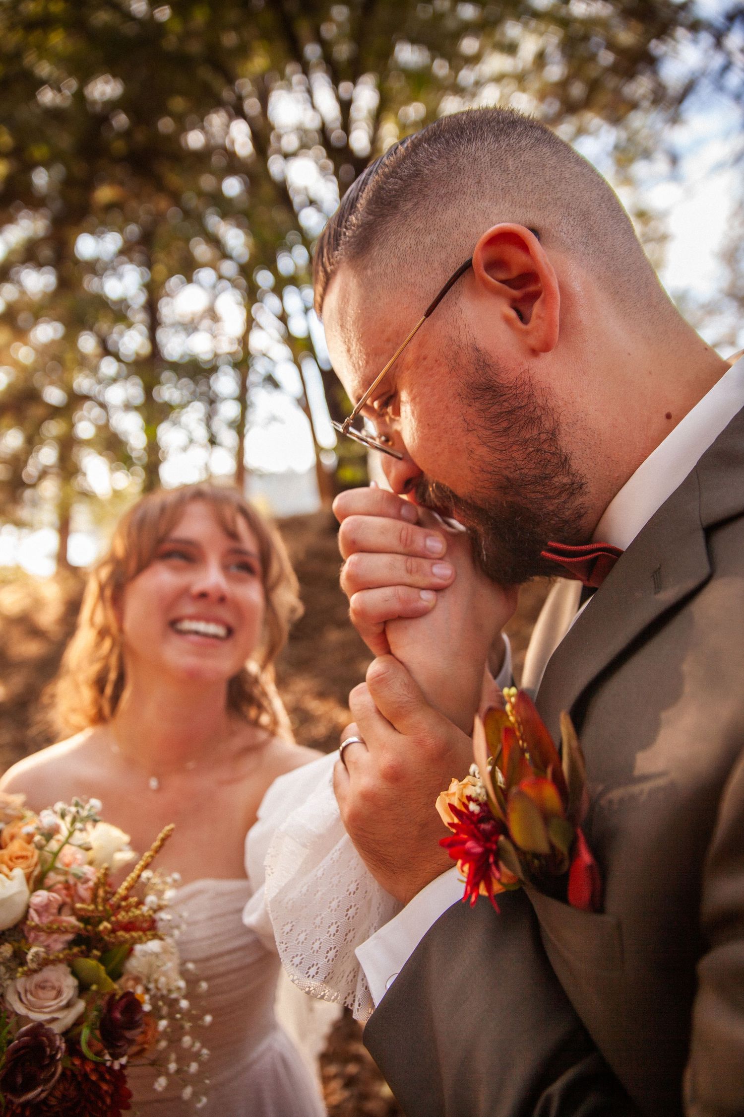Groom kissing bride’s hand while she smiles during an outdoor wedding ceremony in Big Bear California
